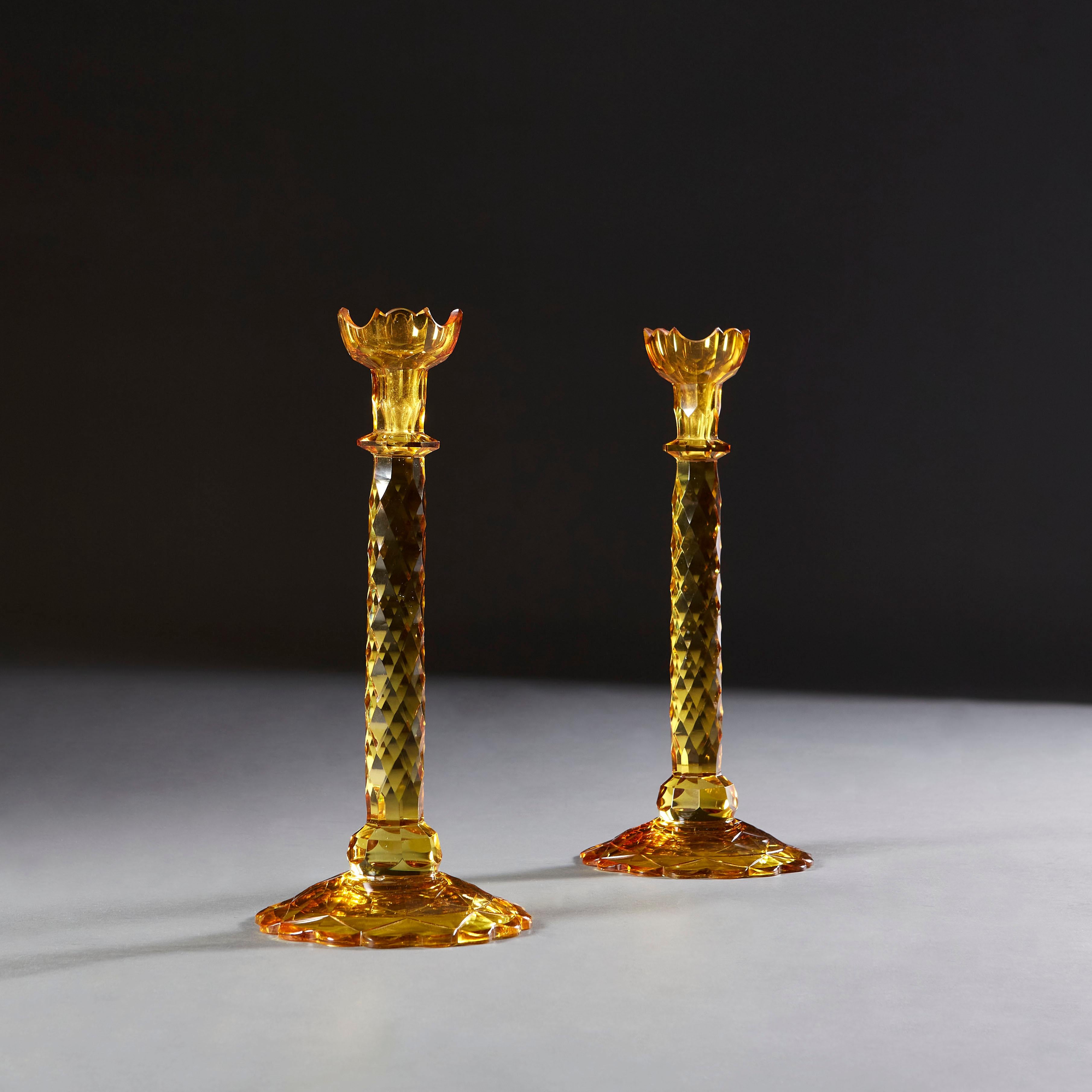 A rare pair of English amber cut glass candlesticks, with tulip form tops, and faceted stem and bases.