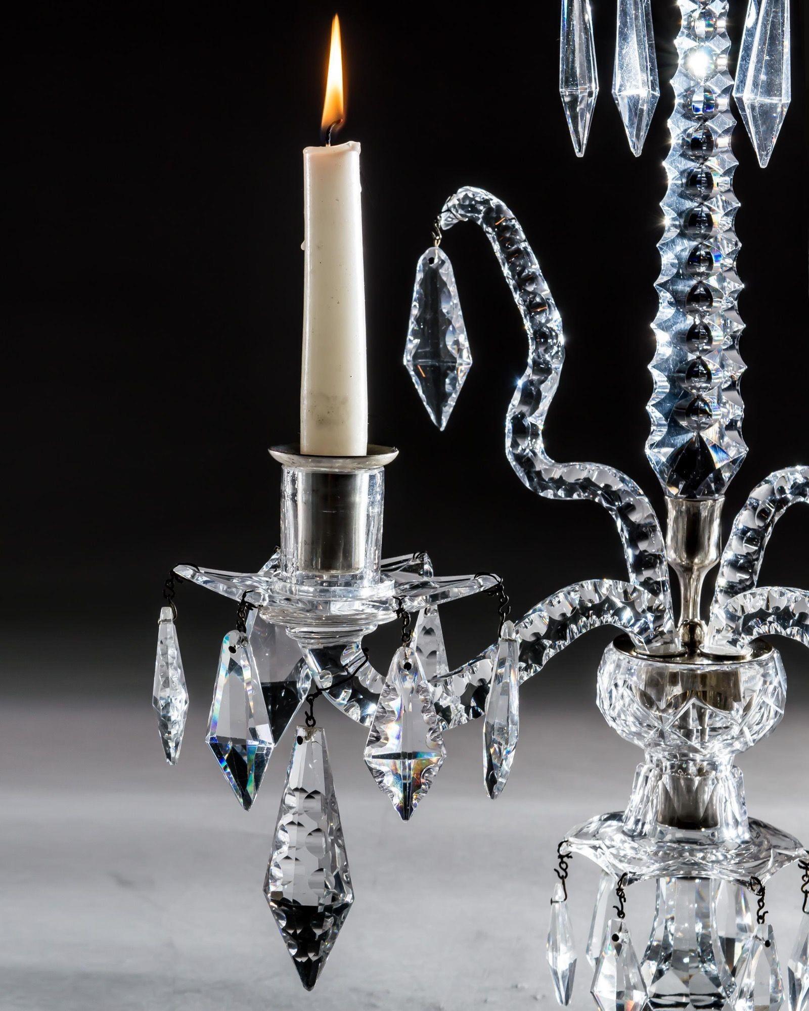 La base, festoneada y ondulada, tiene un dosel colgante coronado por un recipiente plano, de donde salen dos ramas de velas con bandejas de goteo y brazos de serpiente, el candelabro centrado con una aguja dentada que sostiene el dosel colgante y un