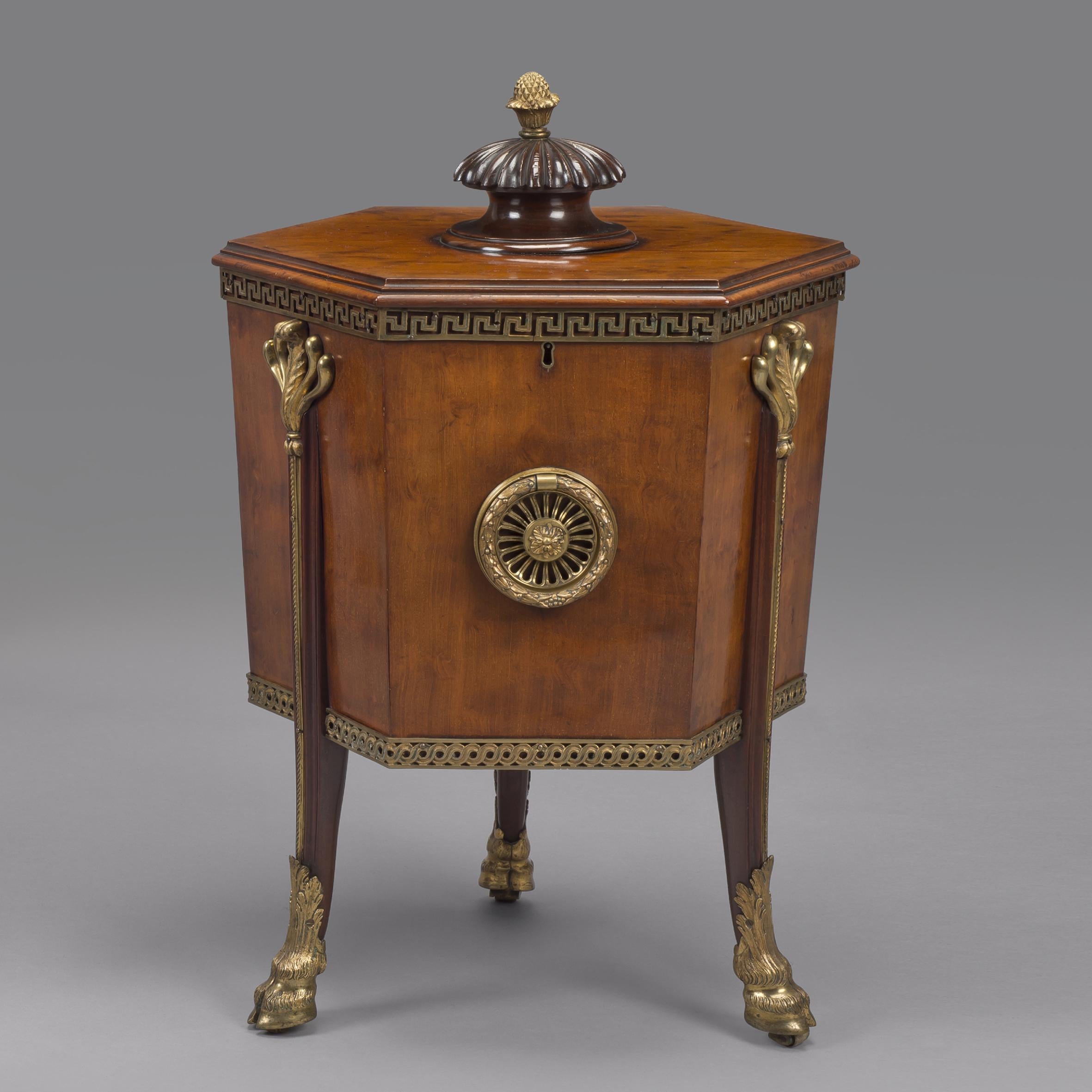 A Rare Pair of George III Style Gilt-Bronze Mounted Mahogany Cellarettes.

This unusual pair of hexagonal cellarets have a hinged top with a knopped finial, opening to an interior fitted with divisions for bottles; the panelled sides are applied
