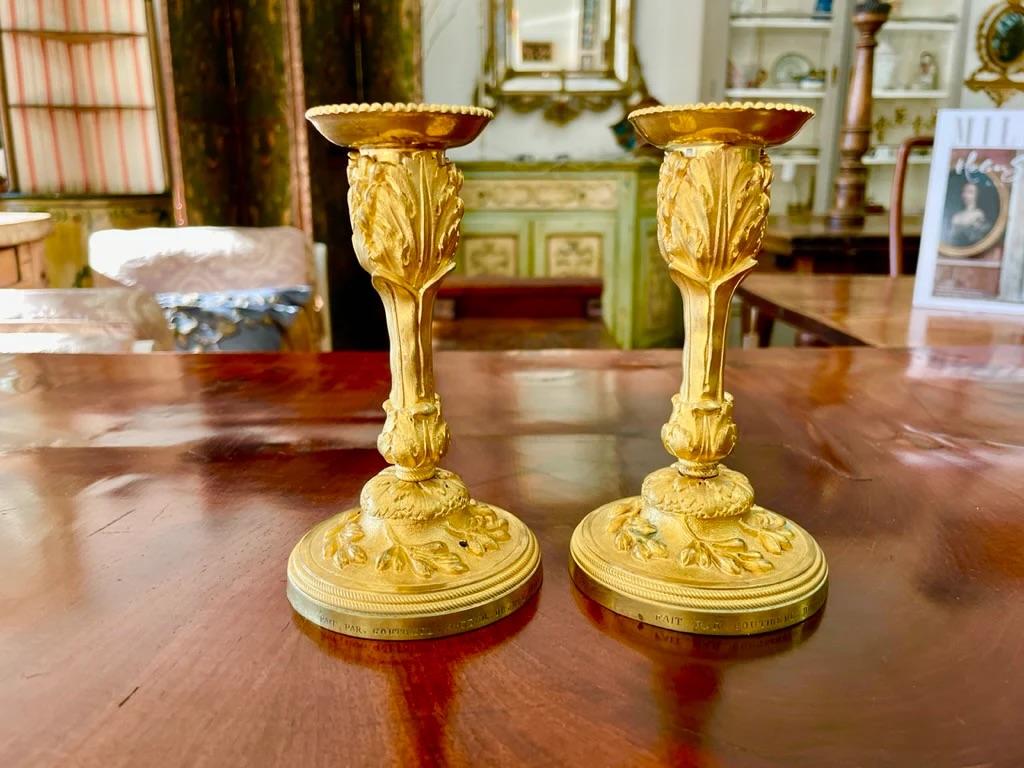 A rare pair of Louis XV gilt bronze candlesticks signed P. Gouthiere. Richly adorned with a foliage relief design with a wide stem and cup shaped tops. Each marked: Fait parGouthiere, Doreur du Roy (gilder to the king), and dated 1769 on the base.