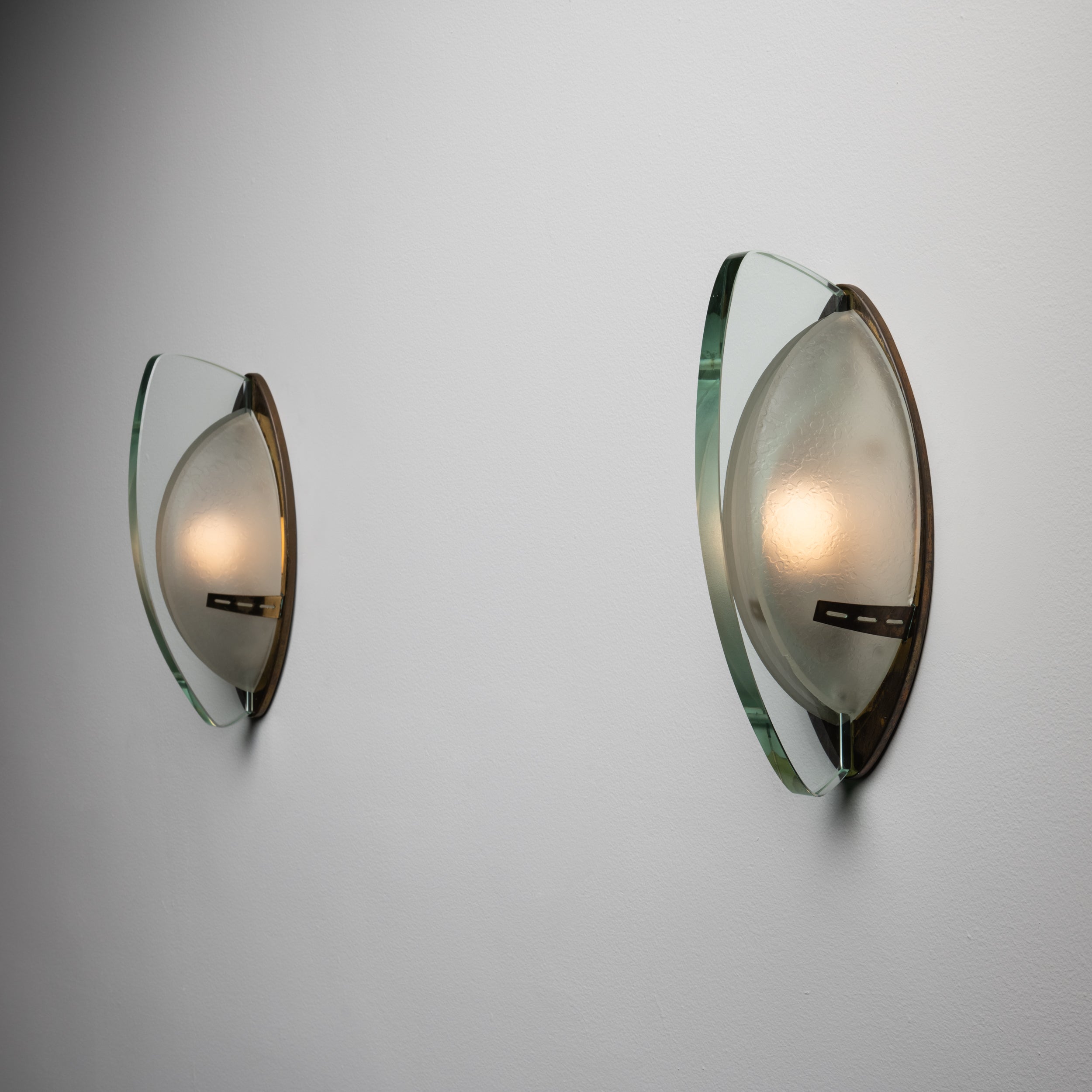 A rare pair of sconces by Stilnovo. Designed and manufactured in Italy, circa 1950's. These sconces feature a brass structure and diffusers in thick ground crystal and satin glass. Rewired for U.S. standards. We recommend two E14 25 w maximum bulbs.