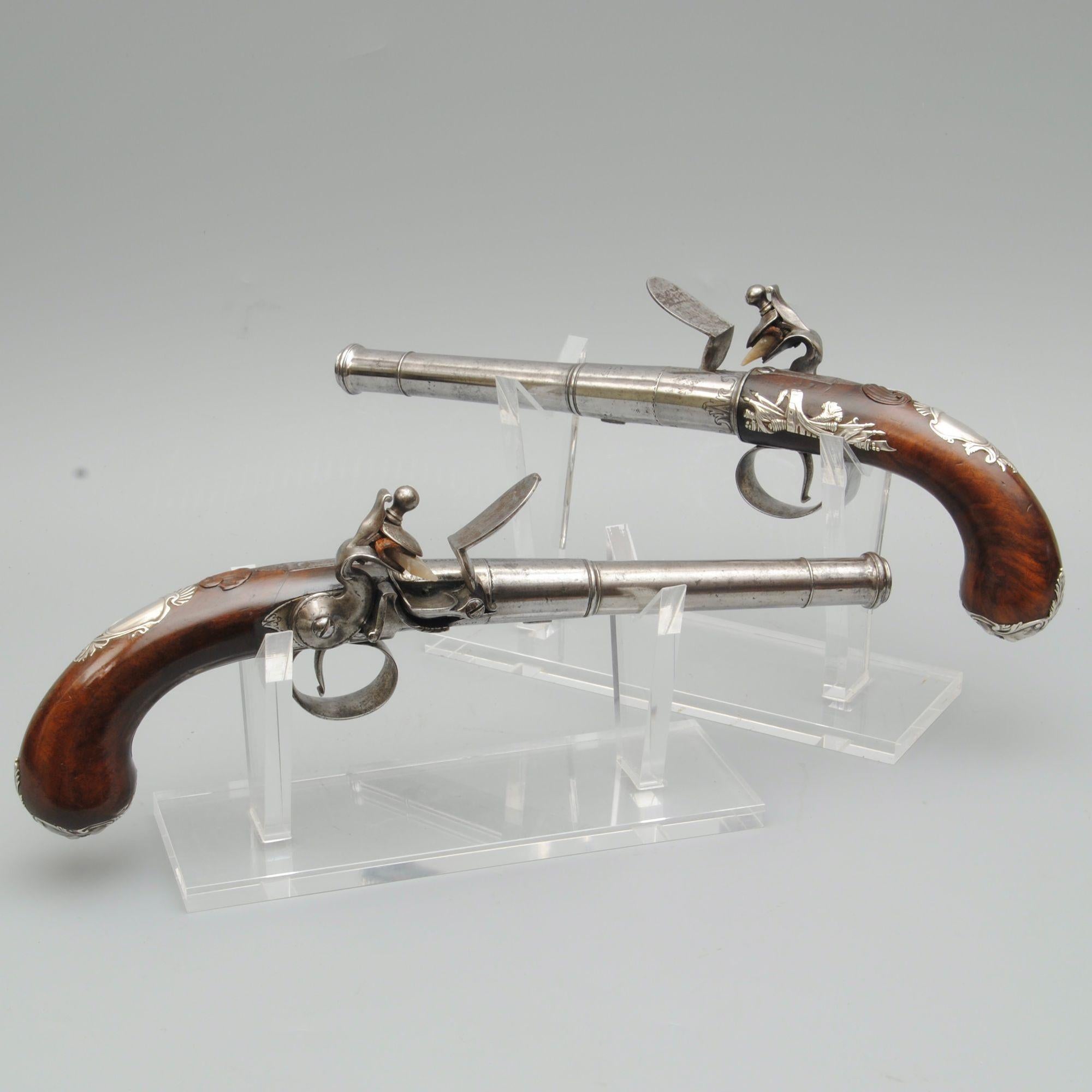 A fine pair of 18th century silver mounted turn off cannon barrel flintlock pistols by George Reed, London. The barrels are numbered and with good proof marks. The well figured walnut stocks with silver mounts including a mask on the butt end, a