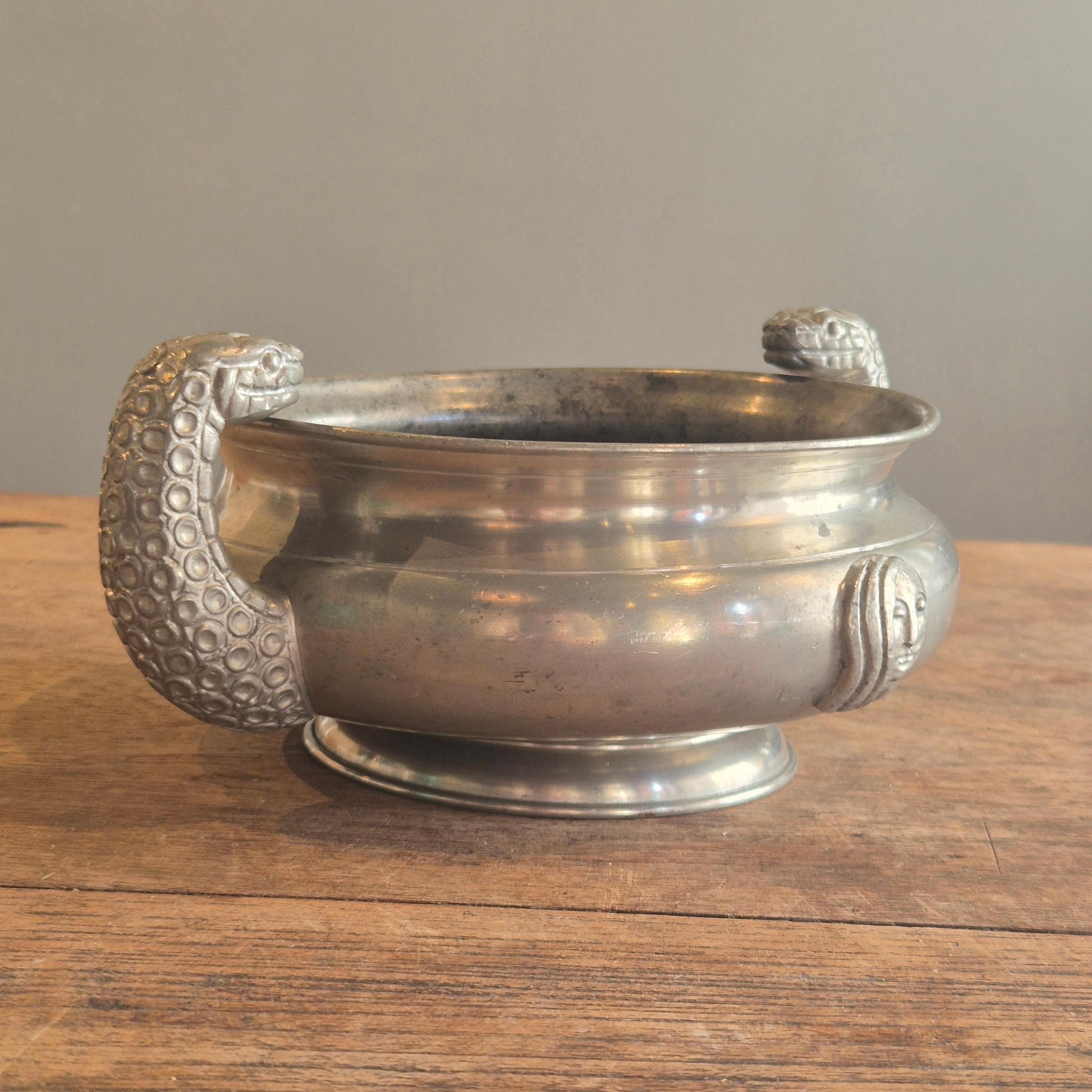 A beautiful solid pewter bowl with snake head handles and decor of a female face. Designed by Anna Petrus for Firma Svenskt Tenn. (celebrates 100 years 2024). With hallmarks and year stamp A8=1927.

This bowl shows Petrus edgy and experimental