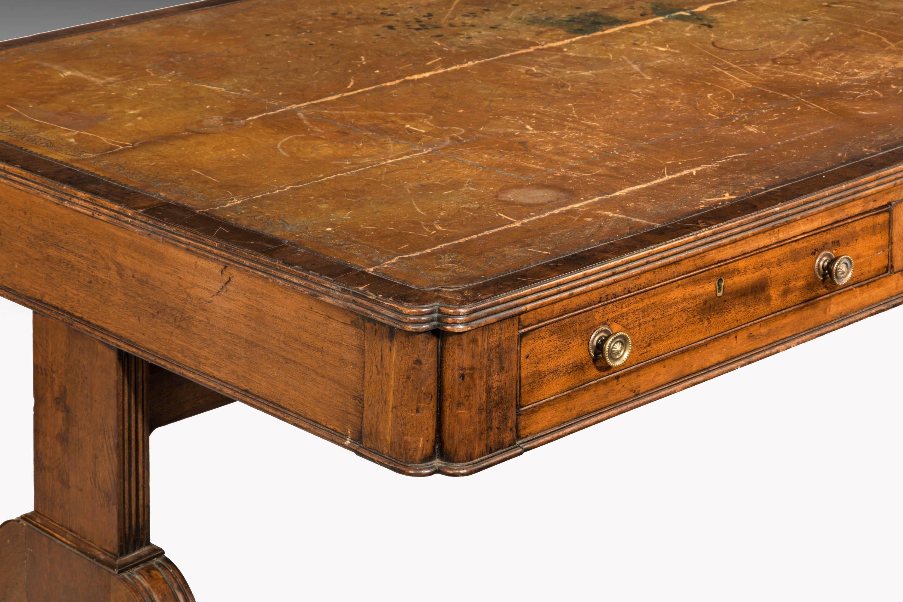 A rare Regency period mahogany library table on end supports. Of quite an extraordinary size with three drawers to each side. The top retaining a somewhat worn and tired but most attractive leather surface. Triple reeded edge to the top. Overall, in