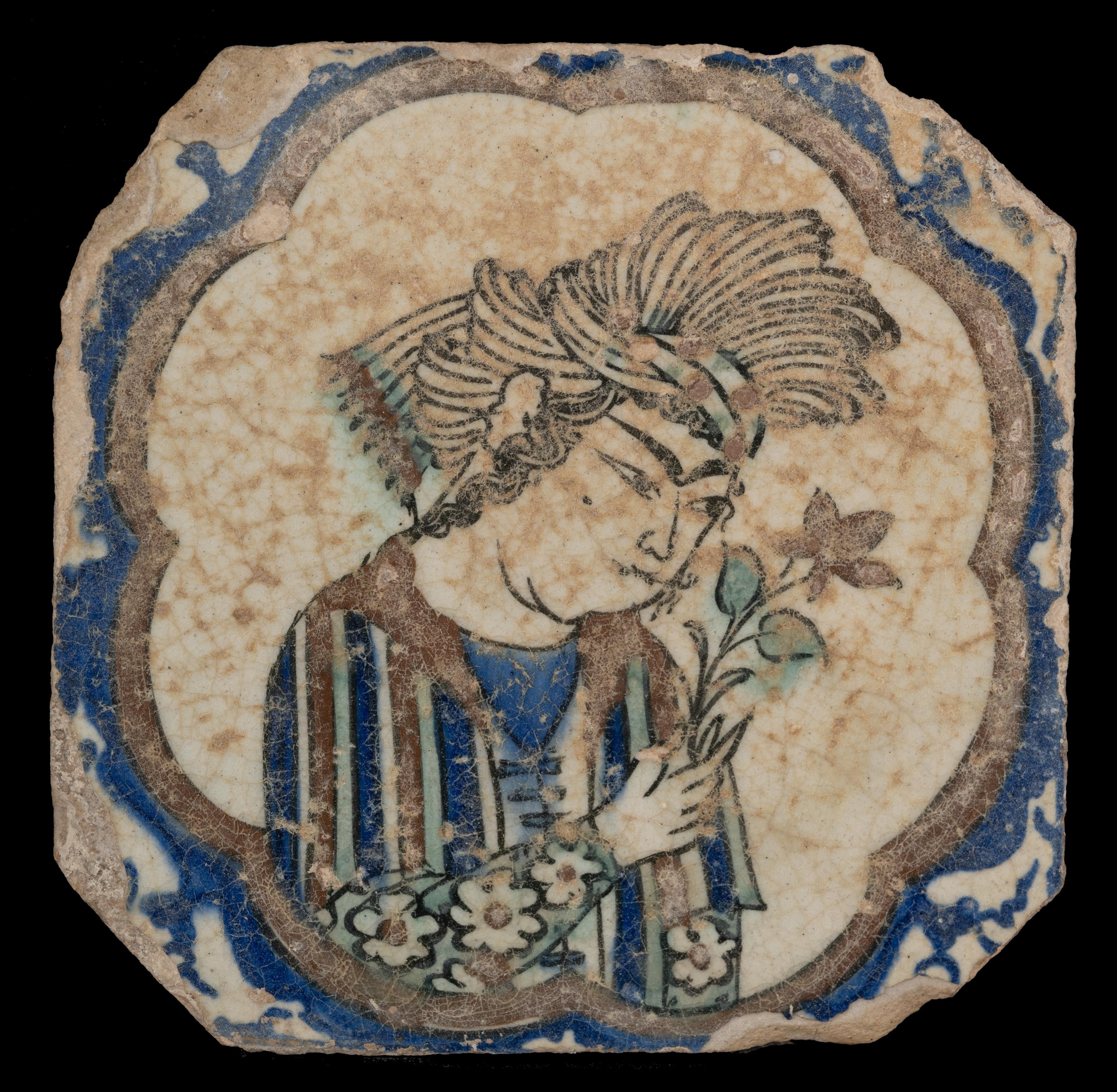 A rare Safavid dynasty (1501-1736) square Kubachi figural pottery tile C 1600.
Tile, with underglaze decoration painted in cobalt blue, green, ochre, and outlined in black, with a central lobed cartouche enclosing a figure holding a flower. Such