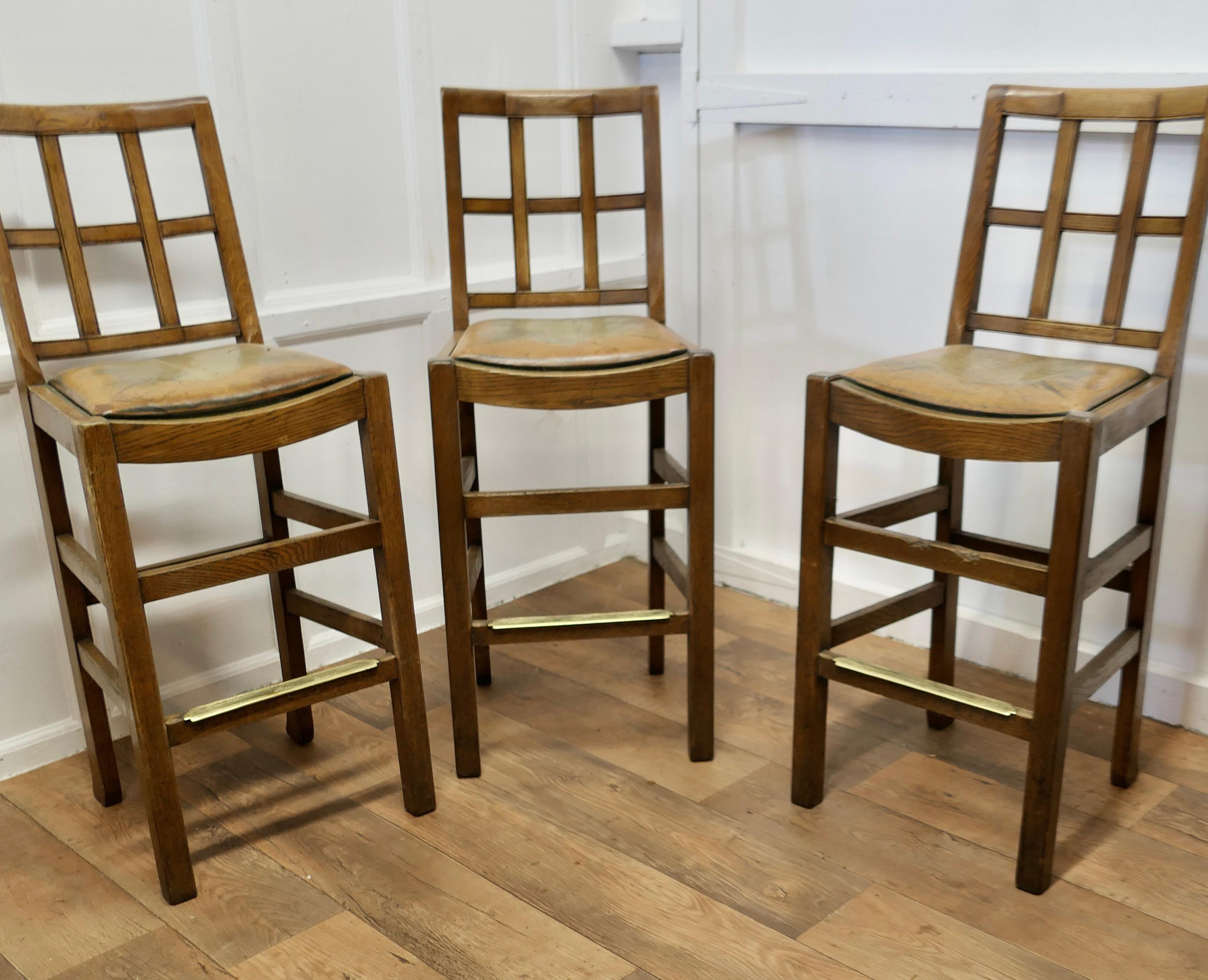 A Rare Trio of Arts and Crafts High Bar Stools, in Golden Oak

A trio of early 20th century oak lattice back dining chairs, probably by Heals, the chairs are in Golden Oak. The chairs have the original Leather seats, now showing a bit of age worn