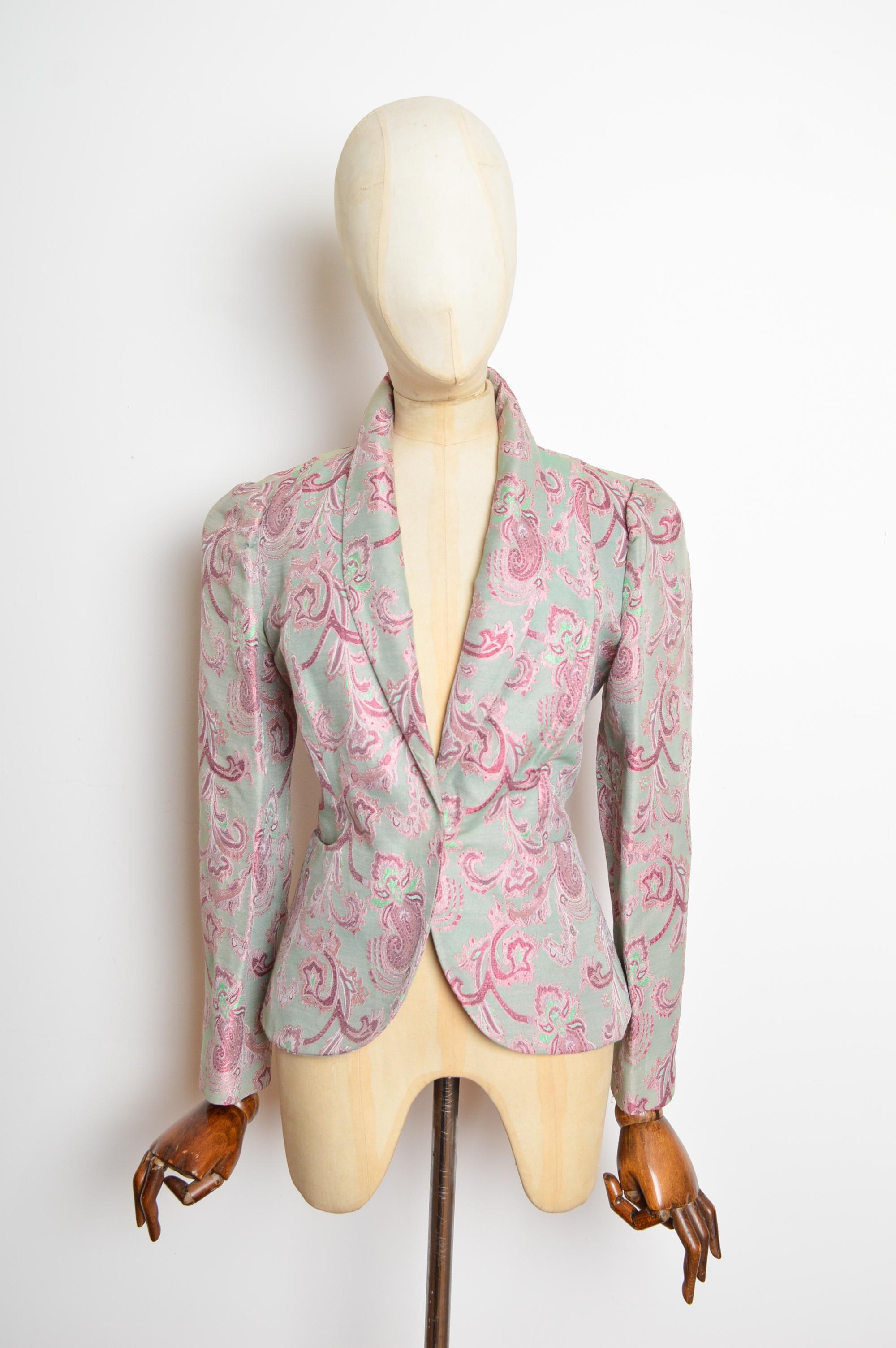 Una magnífica y rara chaqueta vintage de Vivienne Westwood en jacquard azul espuma de mar y rosa empolvado de Paisley.
Las costuras de este extraordinario blazer se ciñen al cuerpo, tiene un sencillo cuello en V y se cierra con un botón a presión en