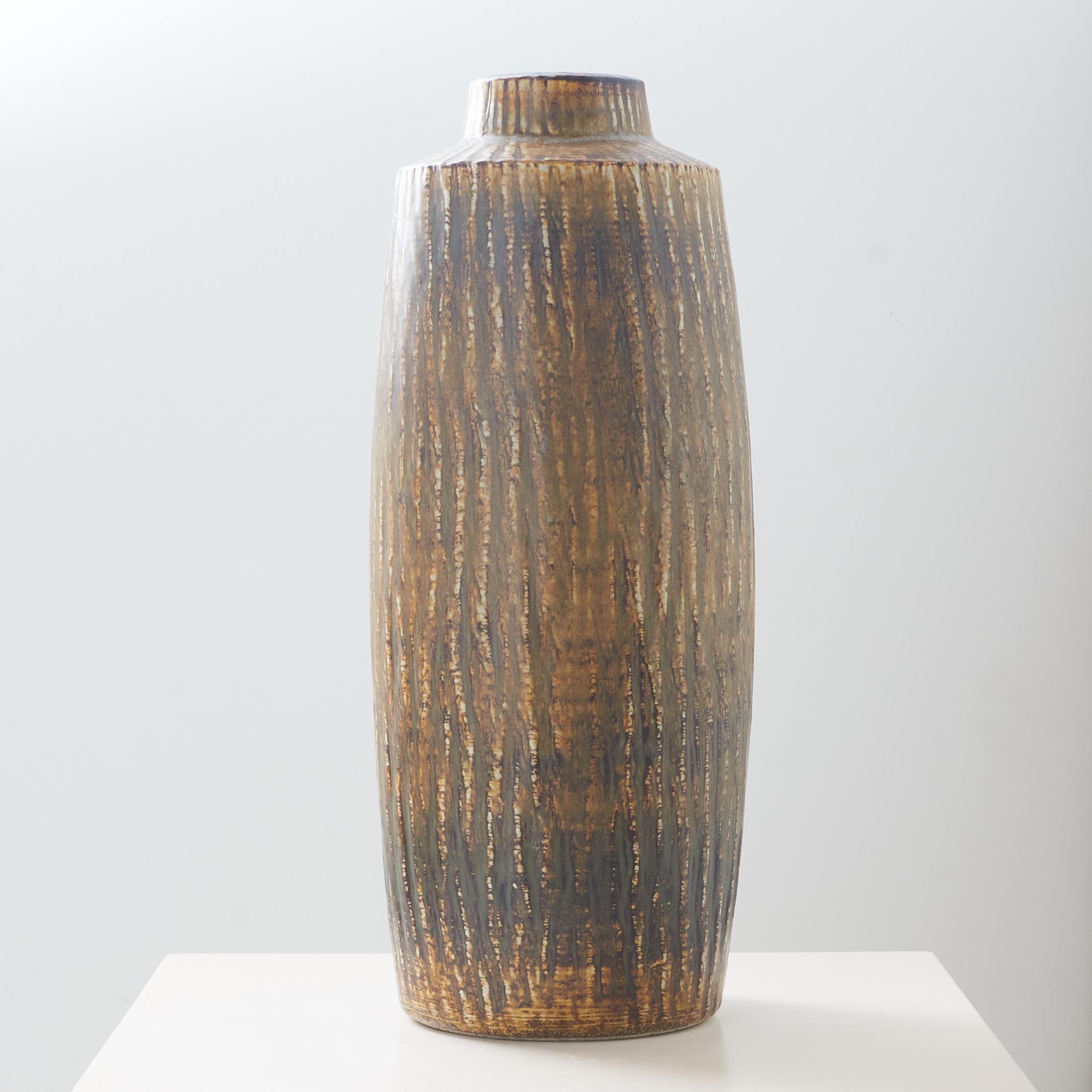 A Rebus series large stoneware floorstanding vase by Gunnar Nylund for Rörstrand. The textural pattern is carved into the piece and finished with a matte glaze of varied light and dark brown tones. Marked on the base. Very good condition.