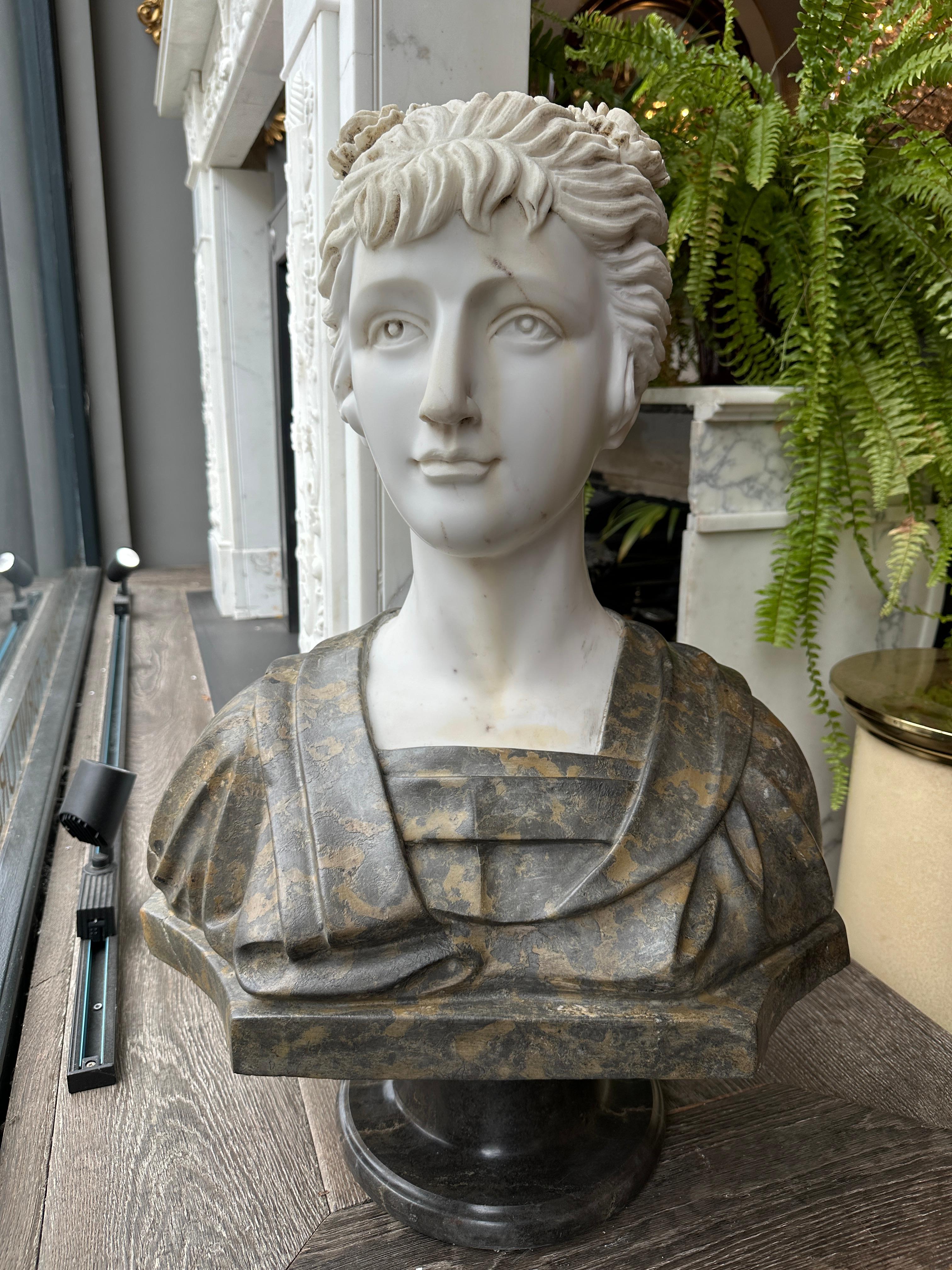 Busto recuperado de estilo neoclásico del siglo XX de figura femenina, la cabeza de mármol Staturio con el pelo hacia atrás y hacia arriba. la túnica de mármol de color abigarrado, apoyada en un zócalo de mármol Emperador. Recuperado de un hotel de