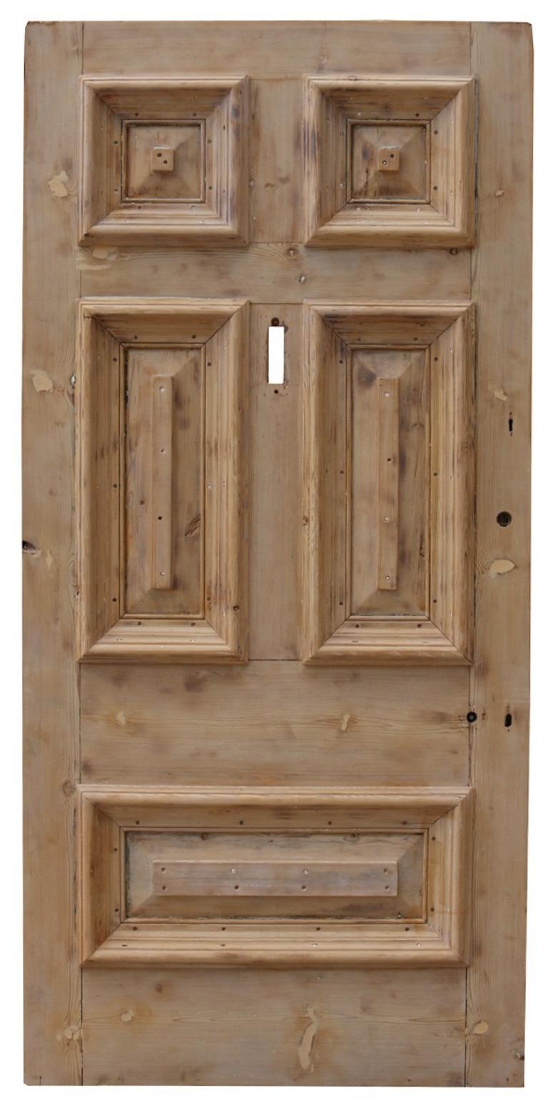 A large reclaimed exterior door, made from pine, with a stripped and sanded finish.