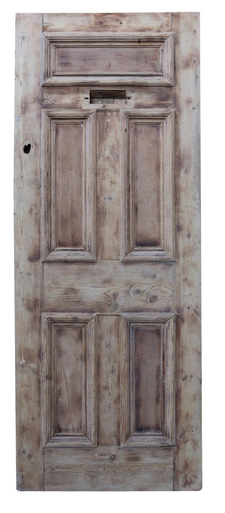 A reclaimed front door, constructed from pine, with a stripped and sanded finish.