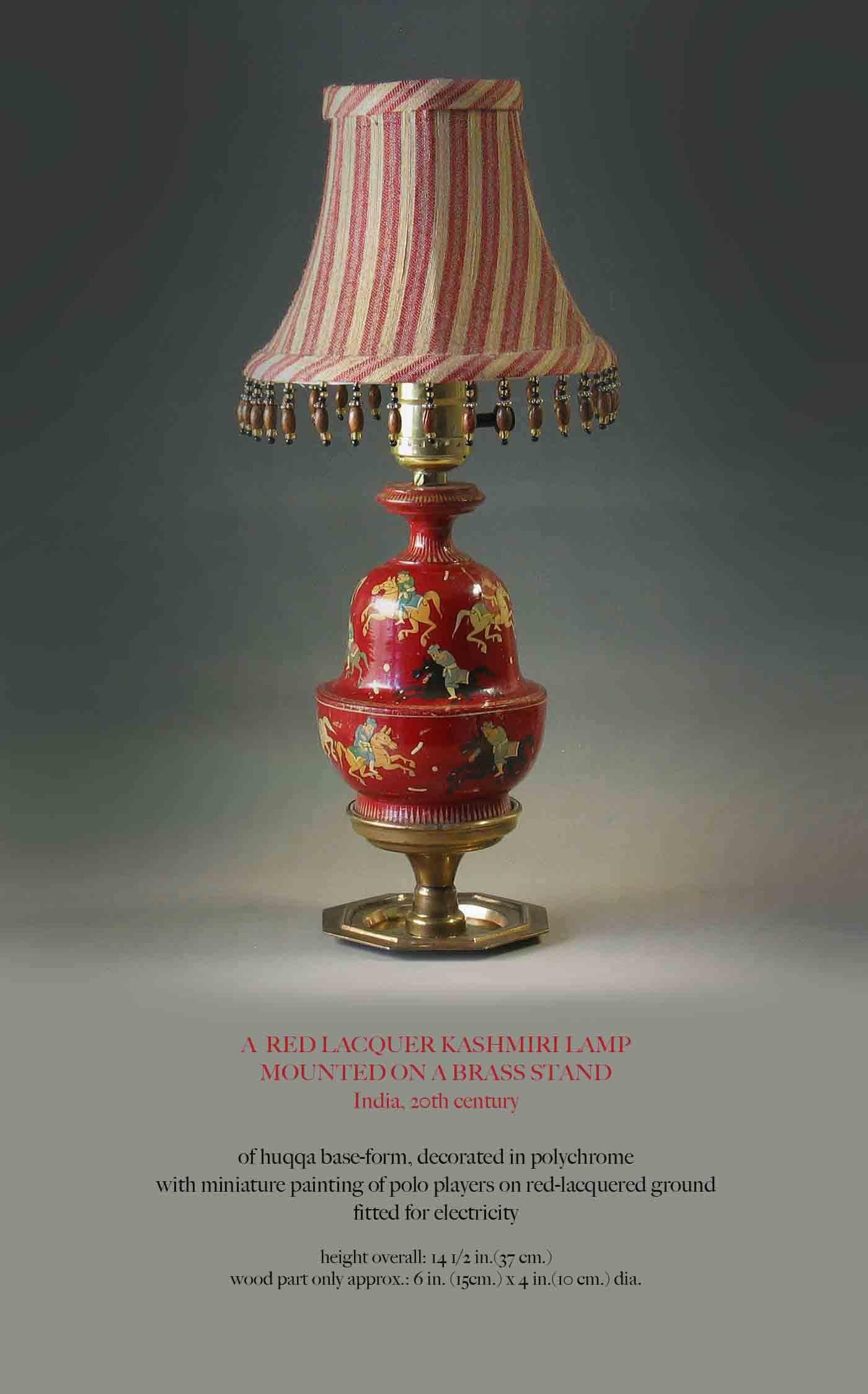 Lampe cachemirienne en laque rouge montée sur un pied en laiton, Inde, XXe siècle. Forme de base Huqqa, décorée en polychromie sur bois avec peinture miniature de joueurs de polo sur sol laqué rouge aménagé pour l'électricité. La lampe mesure 14 1/2