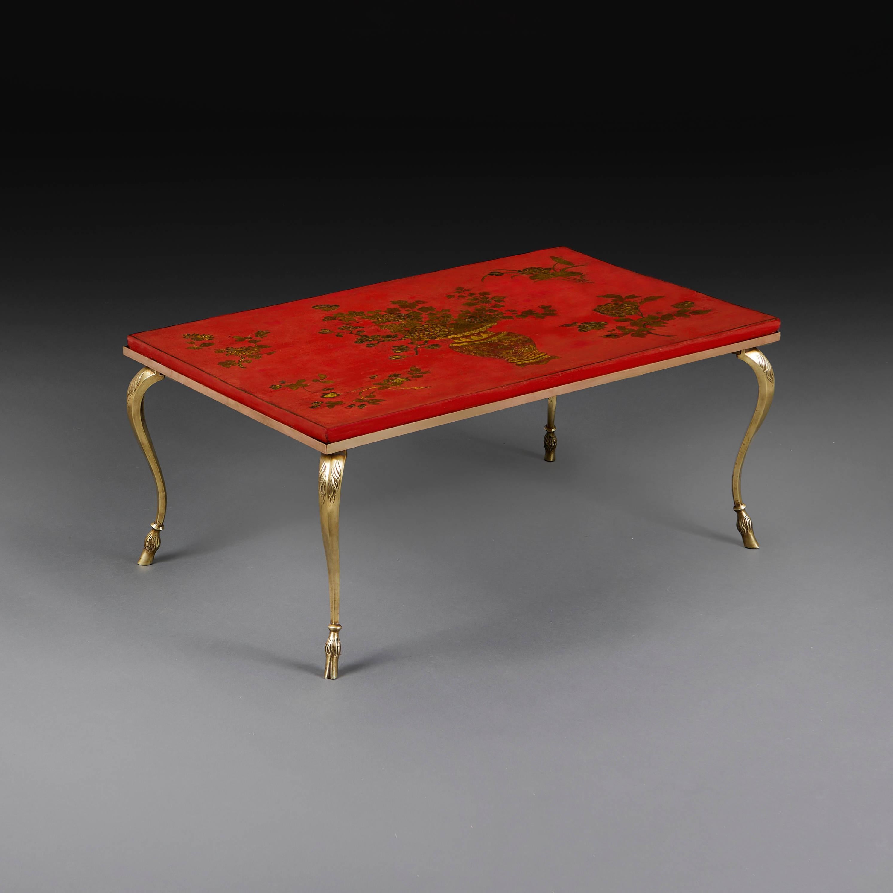 Panneau en laque rouge du début du 20e siècle, décoré d'une urne chinoise tenant une gerbe de fleurs, avec une décoration feuillagée aux angles, monté dans un cadre en laiton avec des pieds en sabot de chèvre. À la manière de la Maison Bagues.
