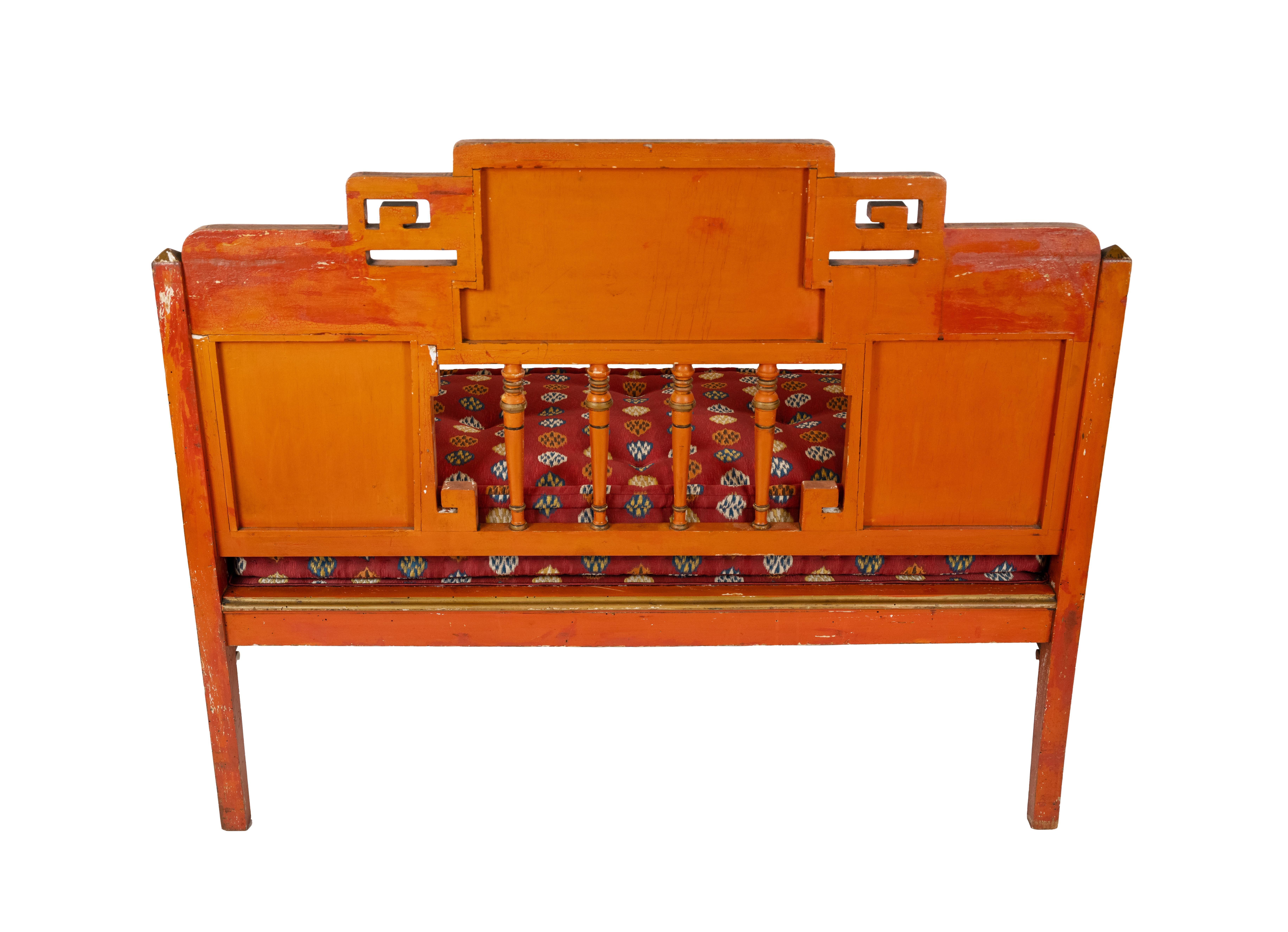 This enchanting early 20th-century red-painted chinoiserie settee showcases exceptional craftsmanship and artistic detailing. Hand-painted scenic panels depict idyllic landscapes, pagodas, and floral motifs, all rendered in a rich black and gold