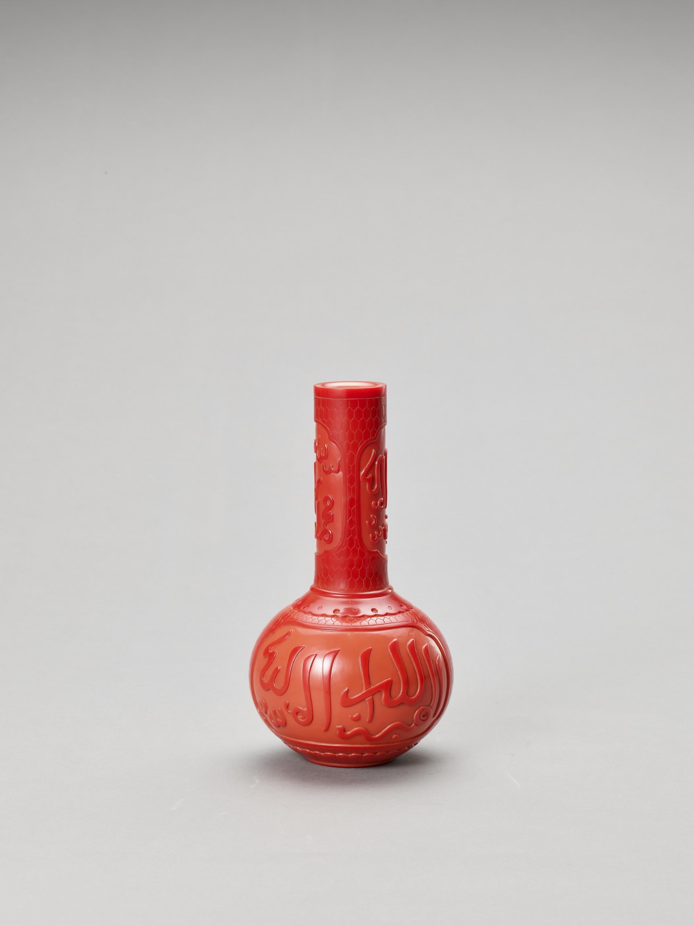 A red peking glass bottle vase for the Islamic Market, China, 20th Century

The globular body and tall neck are carved through the opaque dark red outer layer to the light red body with reserves containing Arabic inscriptions. The base with an