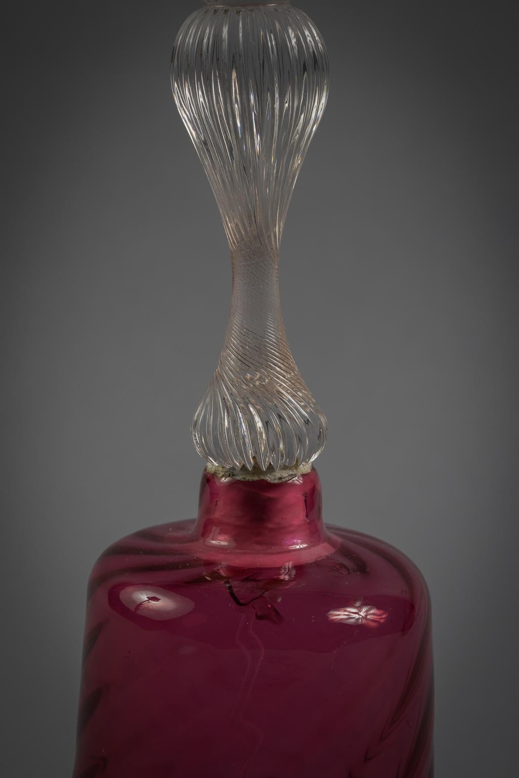 A red spiral blown with a white lip and clear spiral twist handle with clear dripped glass clacker.