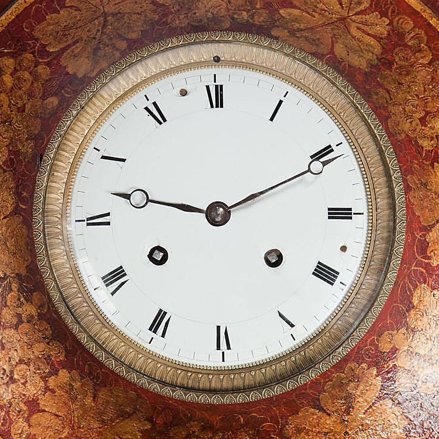 A very fine early 19th century Tole wall clock, the circular bullseye shape with a central white enameled dial within a gilt bronze mount. The clock body finished in red japanning and detailed in gilt. Suspended from a brass ring handle.

France,