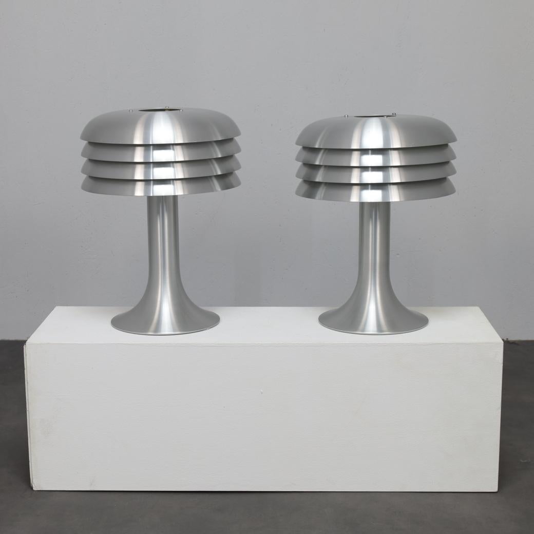 A refined pair of BN 26 table lamps designed by Hans-Agne Jakobsson for AB Markaryd in the 1960s. Executed in brushed aluminium, the lamps display Jakobsson’s signature play of light and shadow through their tiered shades  a sculptural approach that
