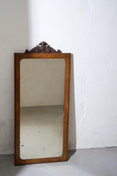 A refined wall mirror featuring a warm wooden frame with elegantly carved crest