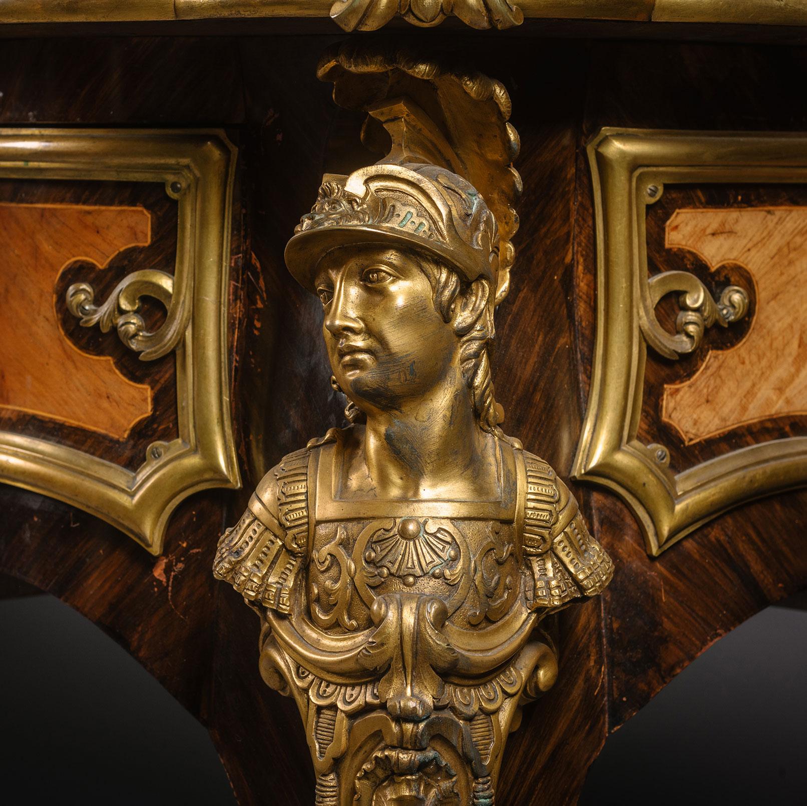 Bureau Plat à Têtes De Guerriers Antiques' - Un important bureau plat monté en bronze doré de style Régence d'après le modèle de Charles Cressent.

Ce grand et élégant bureau plat est doté d'une surface d'écriture en cuir doré, d'un encadrement en