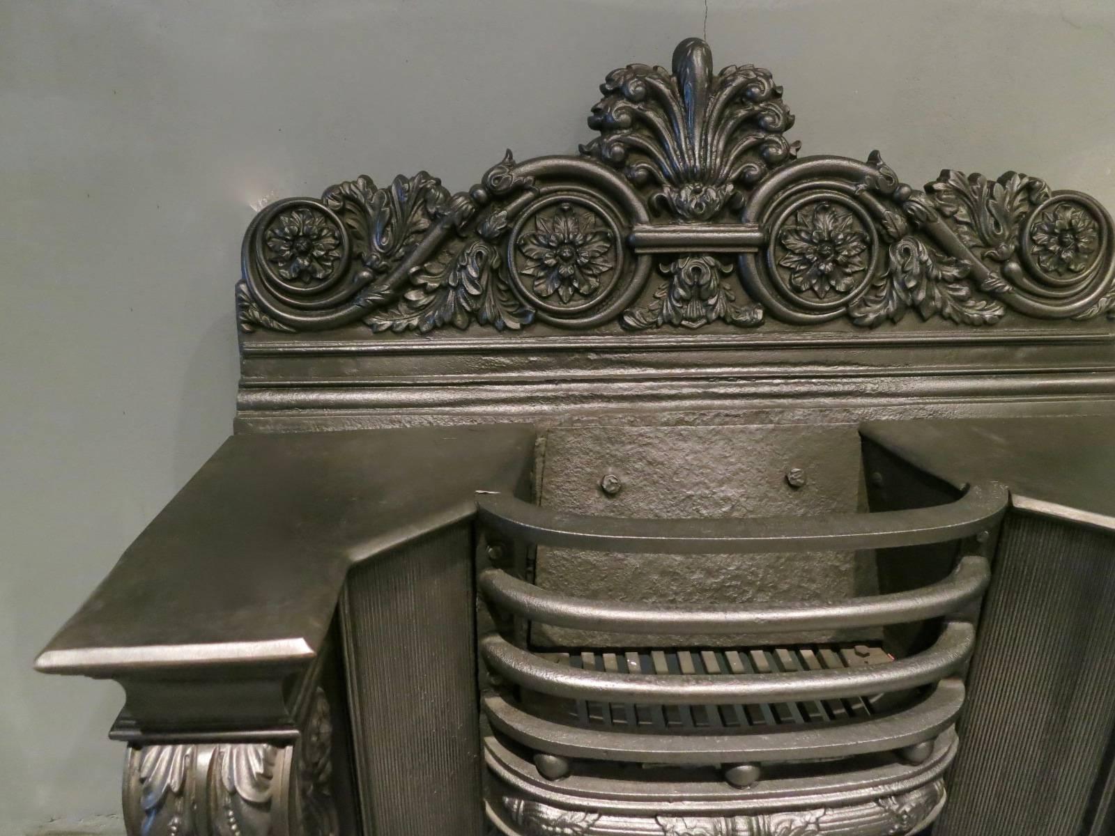 Une grille de foyer finement moulée du début du 19e siècle, à la manière de George Bullock. Les montants de la console, à feuilles d'acanthe enroulées, sont ornés de panneaux en roseau inversé, les barres frontales sont arquées et décorées de boules
