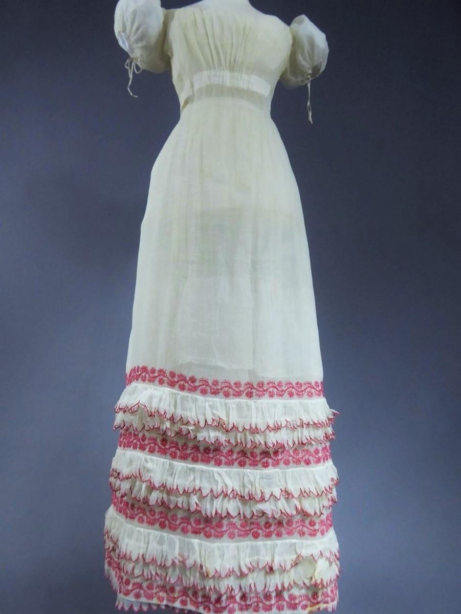 Circa 1815-1820
France or Provence

Rare summer cotton Embroidered Cotton voile dress with cotton thread vermilion dating from the French Première Restauration. Wide balloon sleeves tightened by original Cotton link , like the neckline that attaches