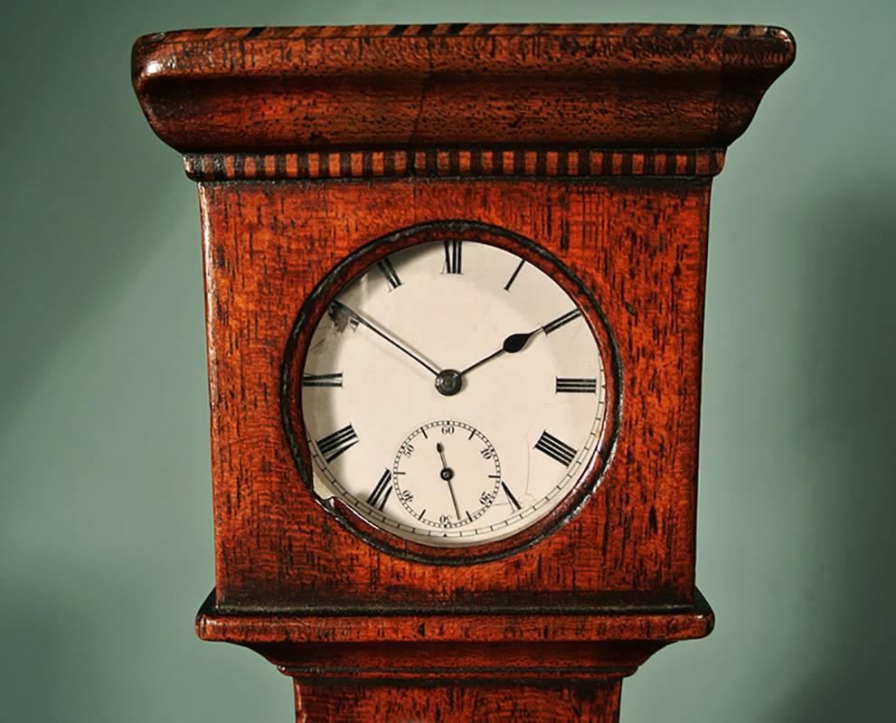 A beautiful pocket watch stand modelled as a long case clock and made from apple wood in circa 1830. 

In excellent original condition with satinwood strung plinth and original green velvet lining to the watch compartment. One small loss to the
