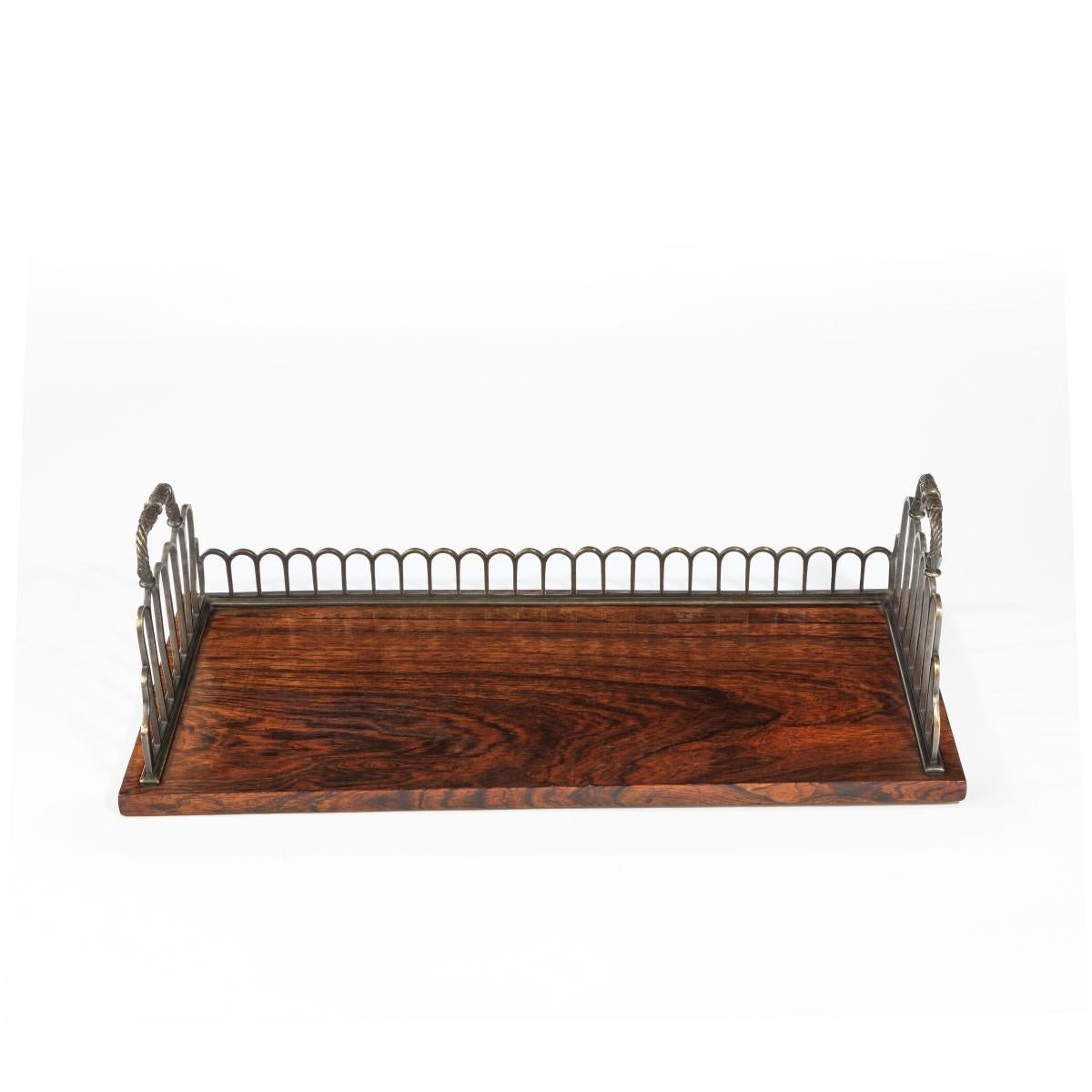 A Regency gilt brass and rosewood book tray, attributed to Gillows, the trellis-cast three quarter gallery incorporating a pair of pierced handles above the rosewood tray section. English, circa 1815.