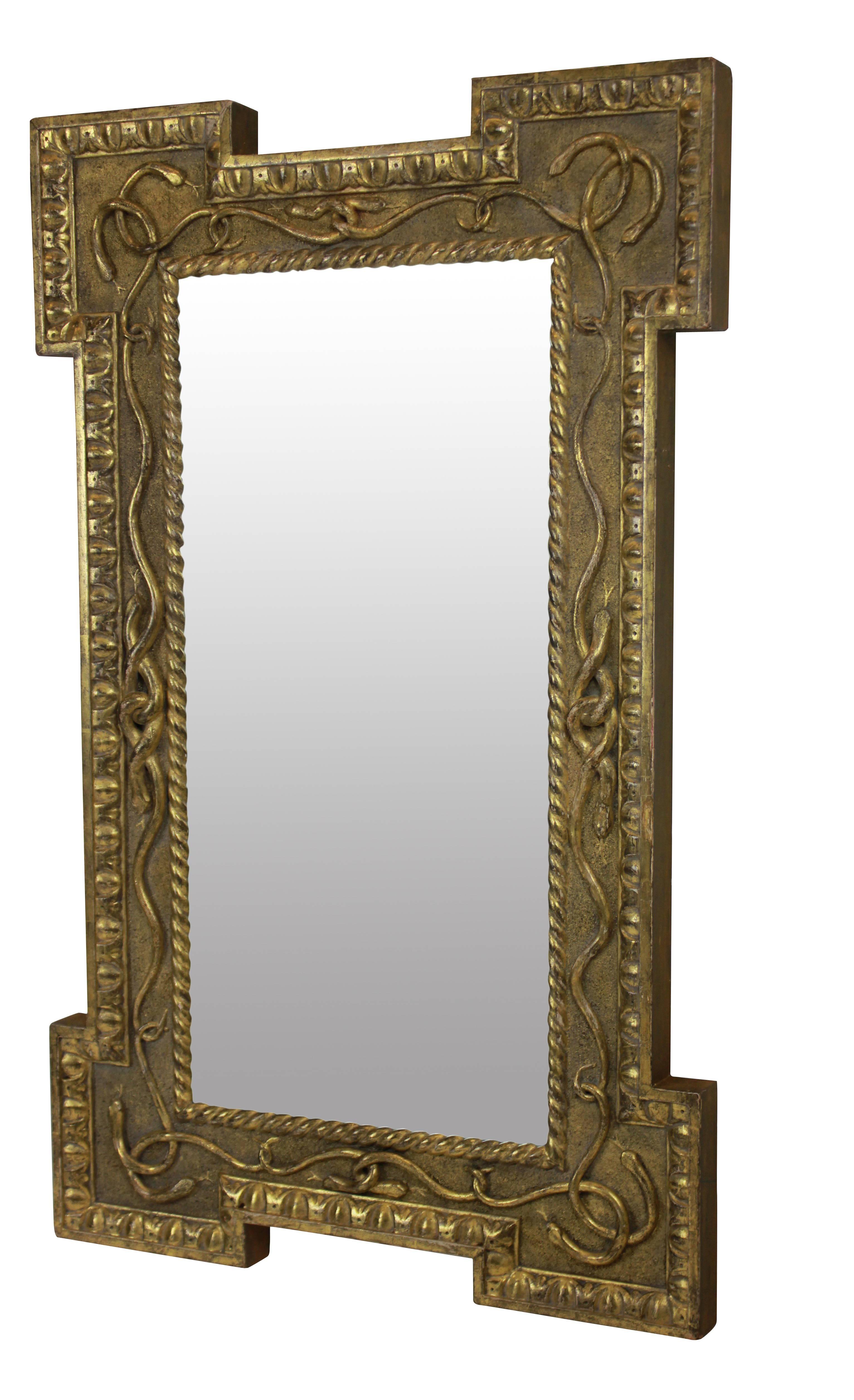 An unusual English Regency mirror in water gilding, depicting entwined serpents. With egg and dart molding, stepped frame and sand coated background.
 