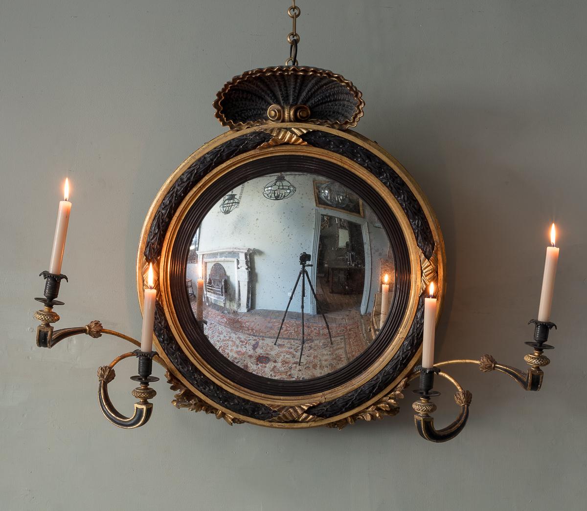 With large scale shell cresting, and darkly contrasting ebonised and giltwood patination, with wildly twisting & scrolling candle arms, accompanied by lightly foxed and gently curving mercury convex plate. (dimensions include widest points with
