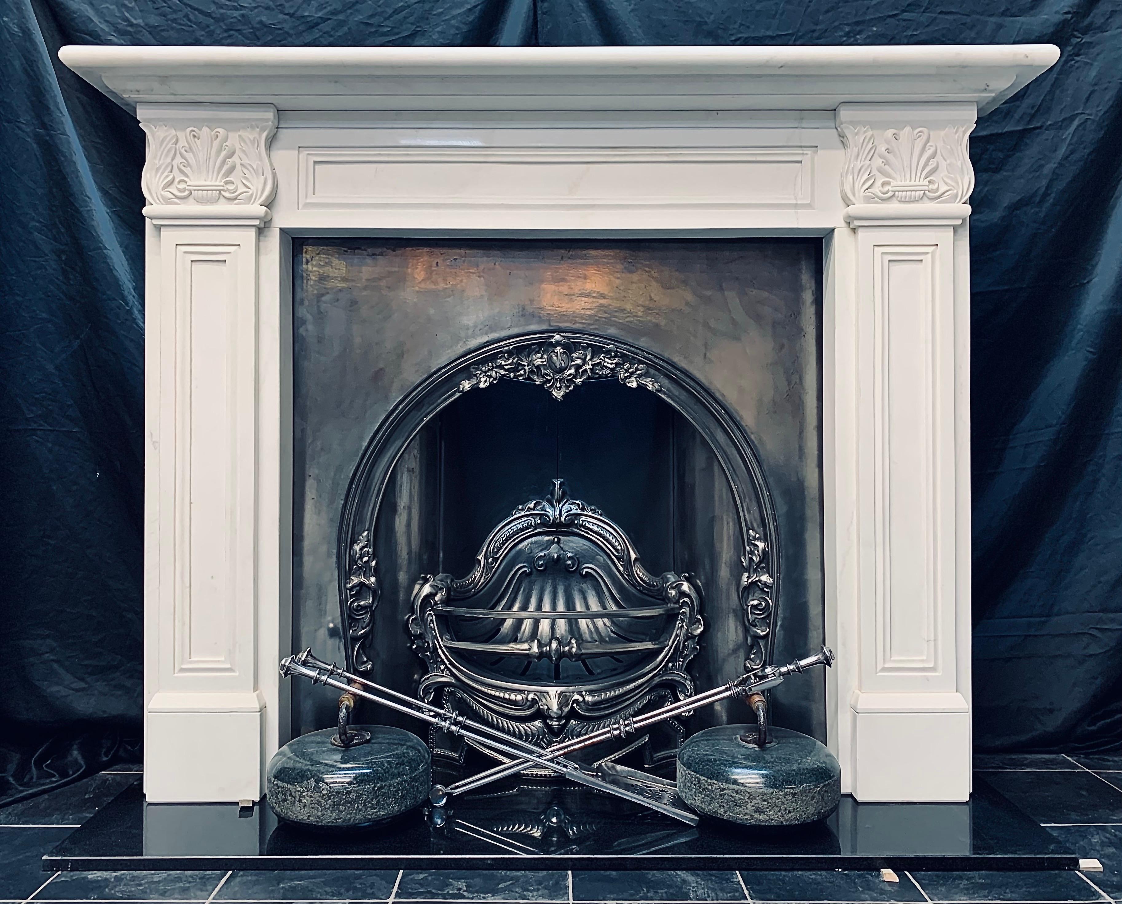 A carved white marble fireplace mantel complete with a cast iron horseshoe fireplace insert with an internal scallop fire grate, in the English Regency Greek Revival manner with recessed panels and carved high relief anthymion end blocks.

Fire