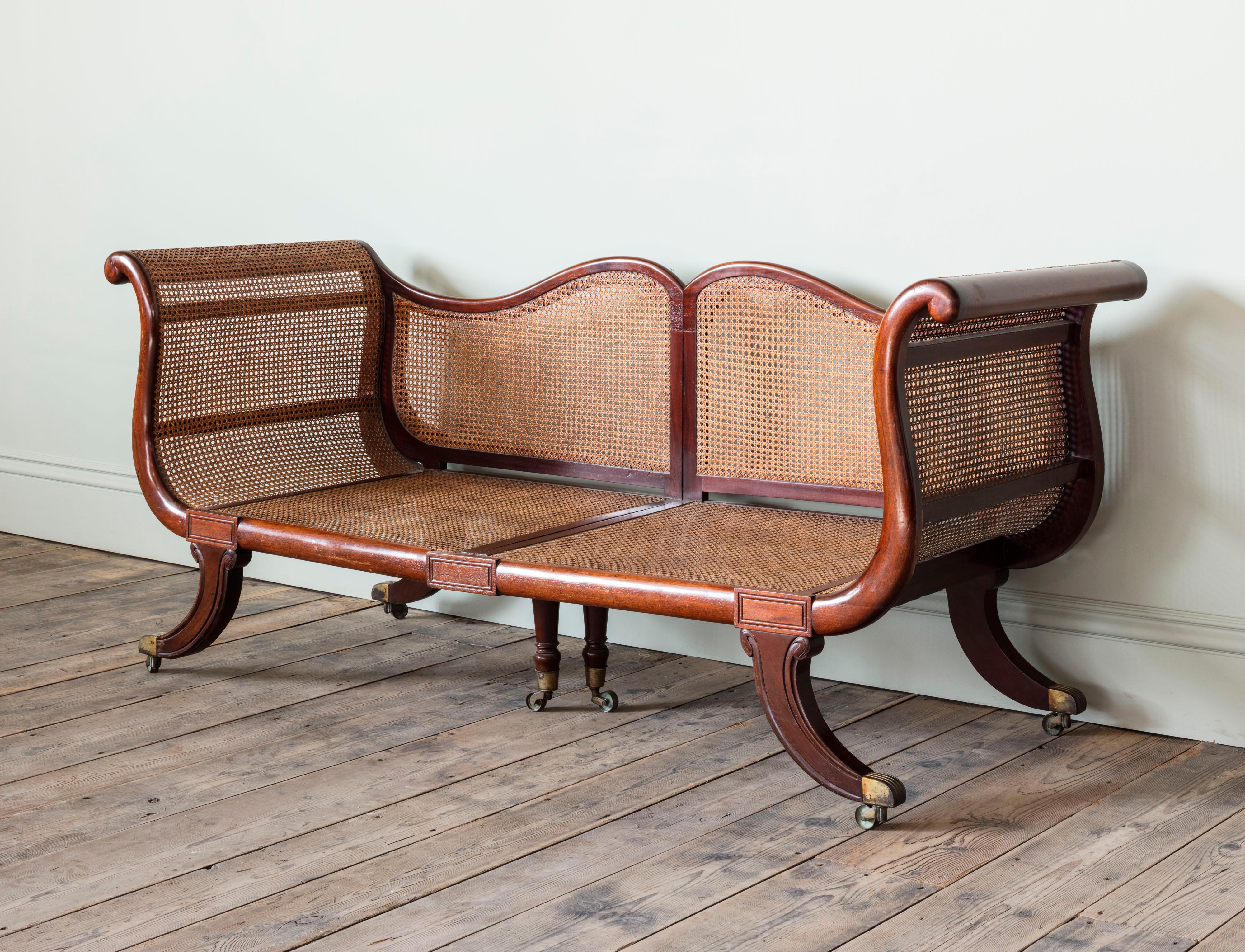 With curved back and outscrolling arms on moulded sabre legs and brass casters. The two halves joined in campaign manner by brass thumb screws, the seat and back would suit squab and fitted cushions.