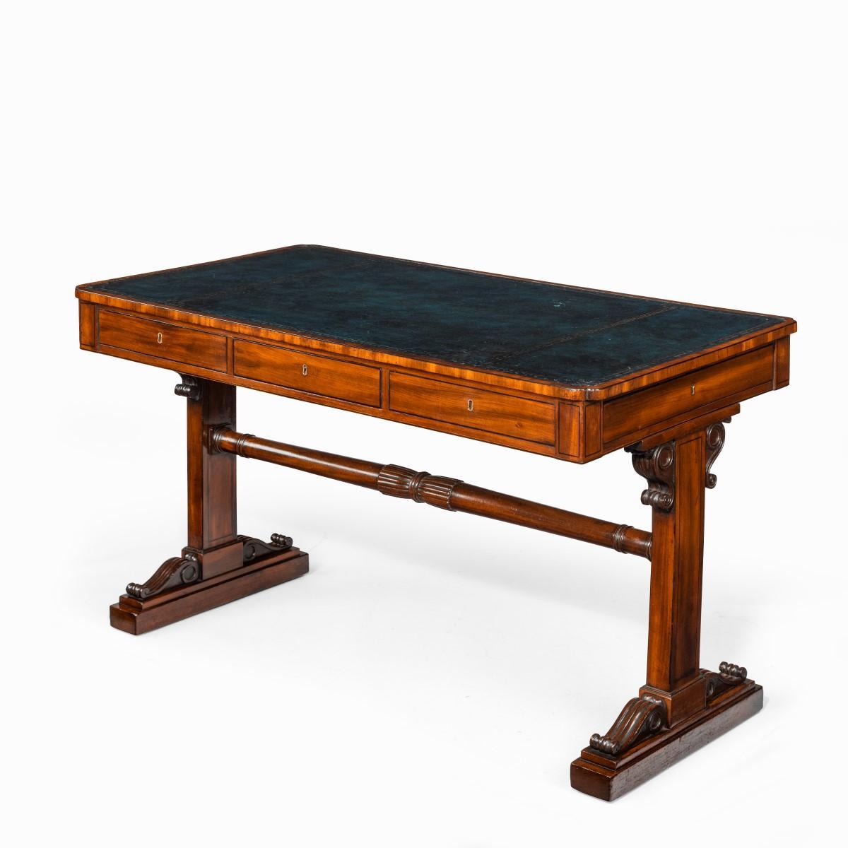 A Regency mahogany end support library table, the rectangular top extensively inset in tooled leather above a frieze with drawers opening on all four sides, the solid rectangular supports with bold scrolling corbels and joined by a turned, tapering