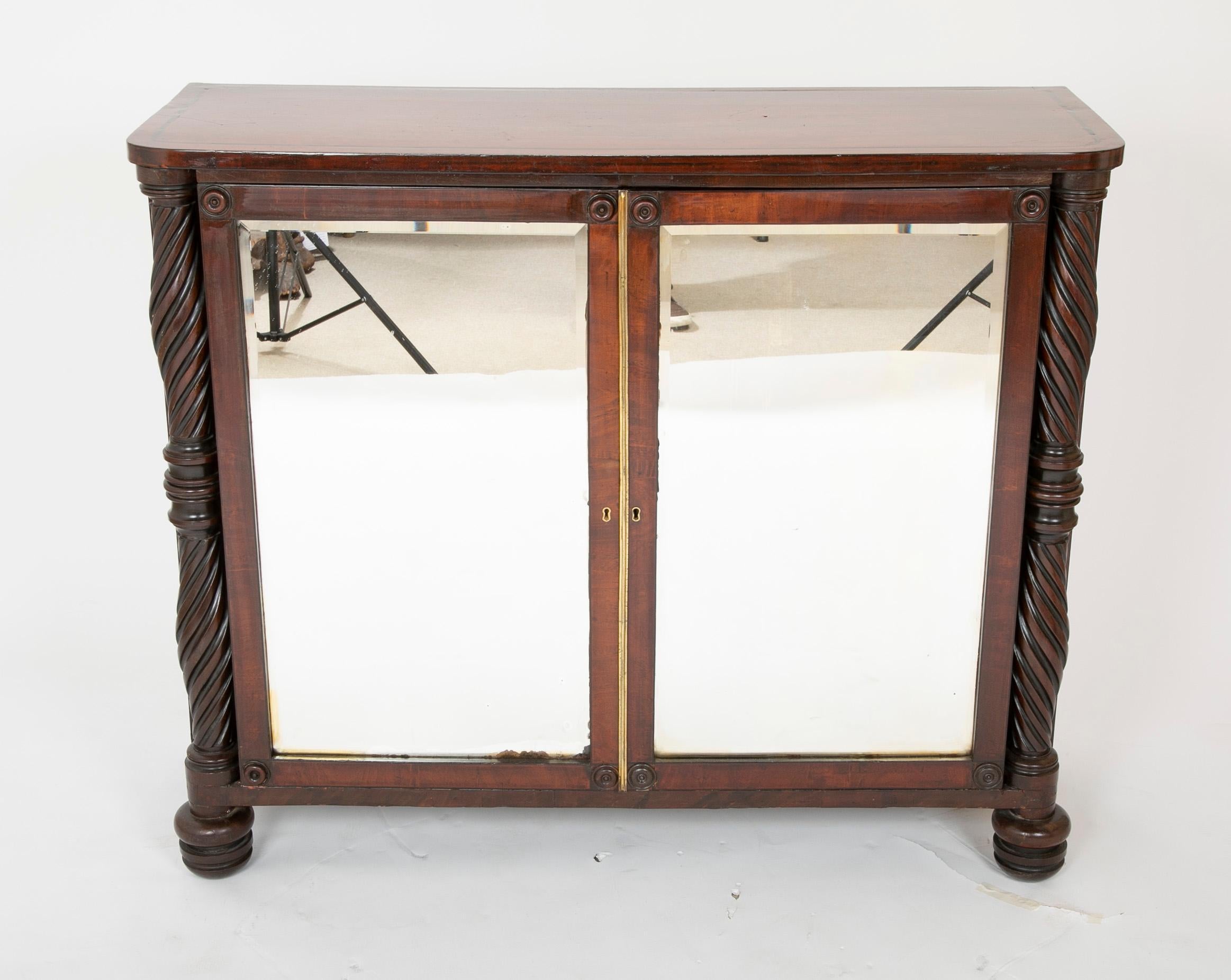 A Regency mahogany mirror door credenza with rope turned corner columns, turned feet & rondels having interior shelves and silver drawer, circa 1820.