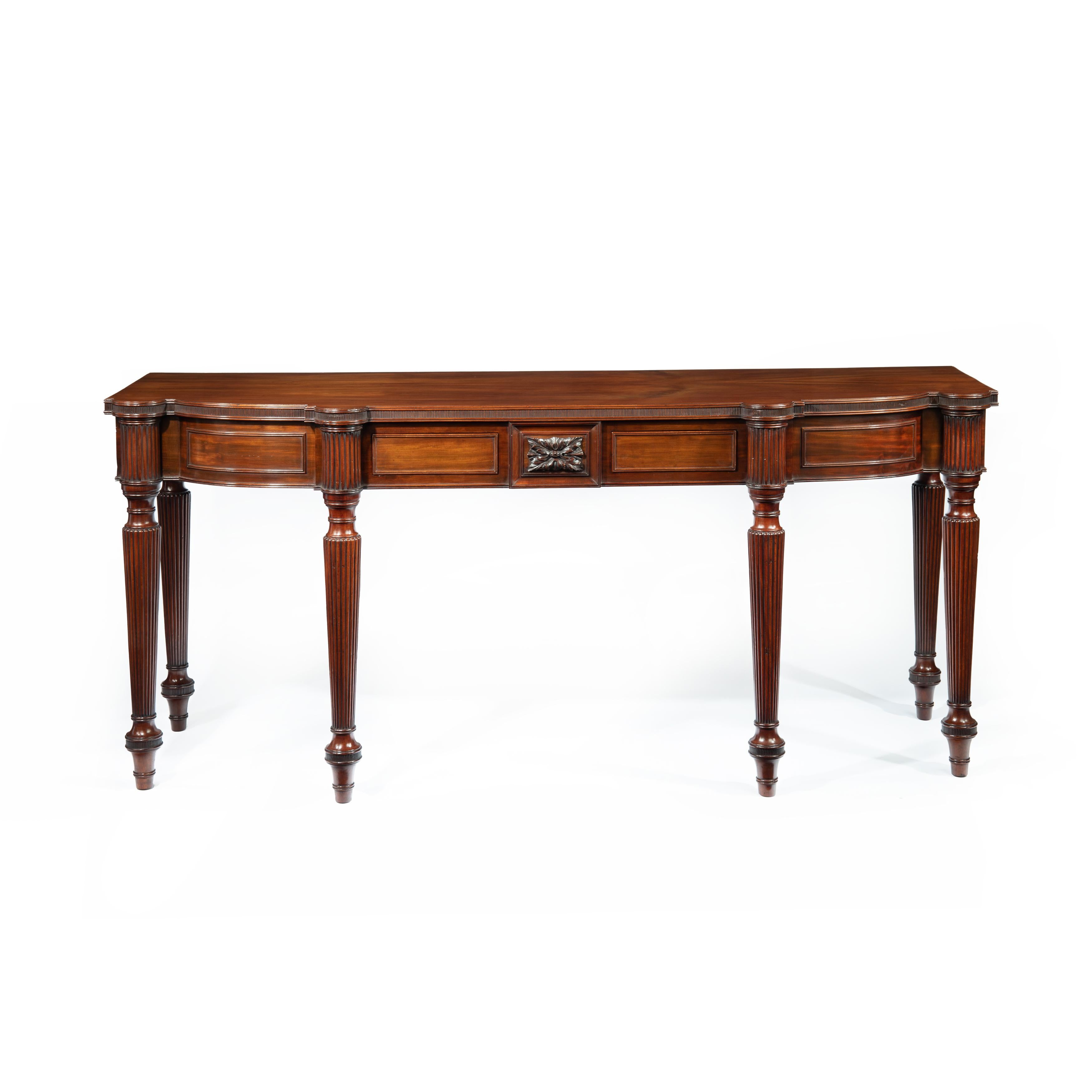 A Regency mahogany serving table attributed to Gillows, the shaped rectangular top with two small drawers and a central acanthus panel in the frieze, all raised on six turned and reeded legs. English, circa 1815.

Footnote: Gillows of Lancaster,