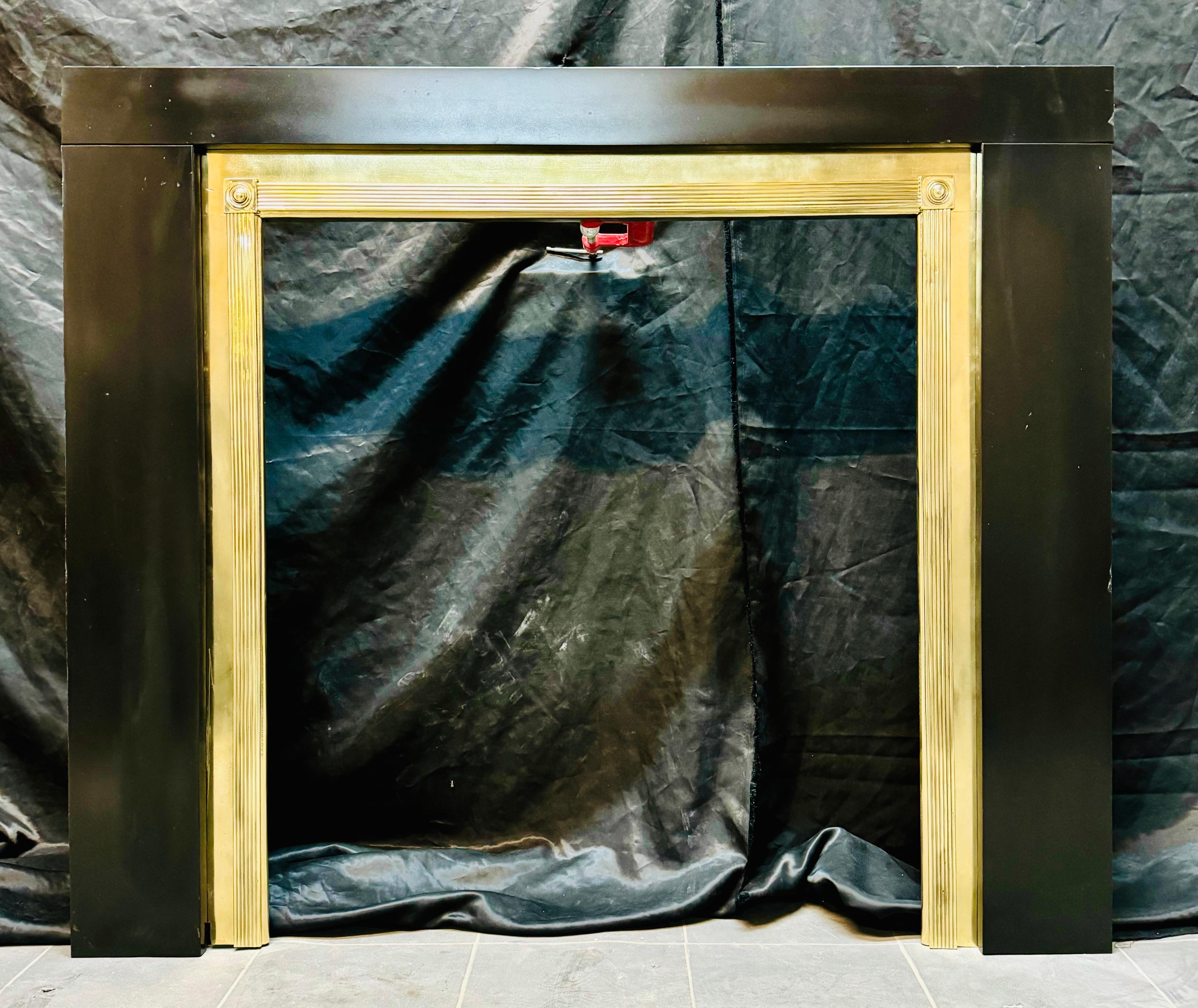 A Regency Manner Polished Brass Fireplace Frame. A versatile brass frame with bullseye capitols and reeded sections to jambs and frieze. Set within a slate frame. This would suit a fire grate or a wood burning stove. 

Brass frame: overall sizes 36”