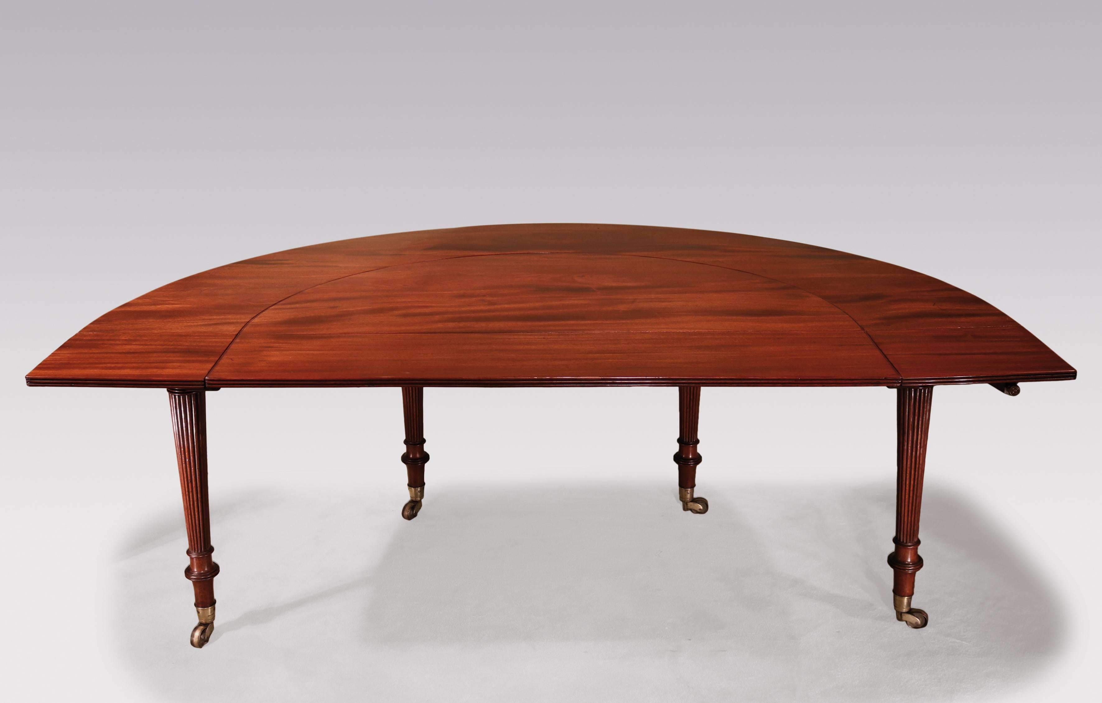 An early 19th century Regency period figured mahogany “Gillows” “Social” or “Wine” table of reeded edged horseshoe shape retaining original centre leaf, fitted with revolving brass arm holding red papier mâché coasters. The Table supported on finely