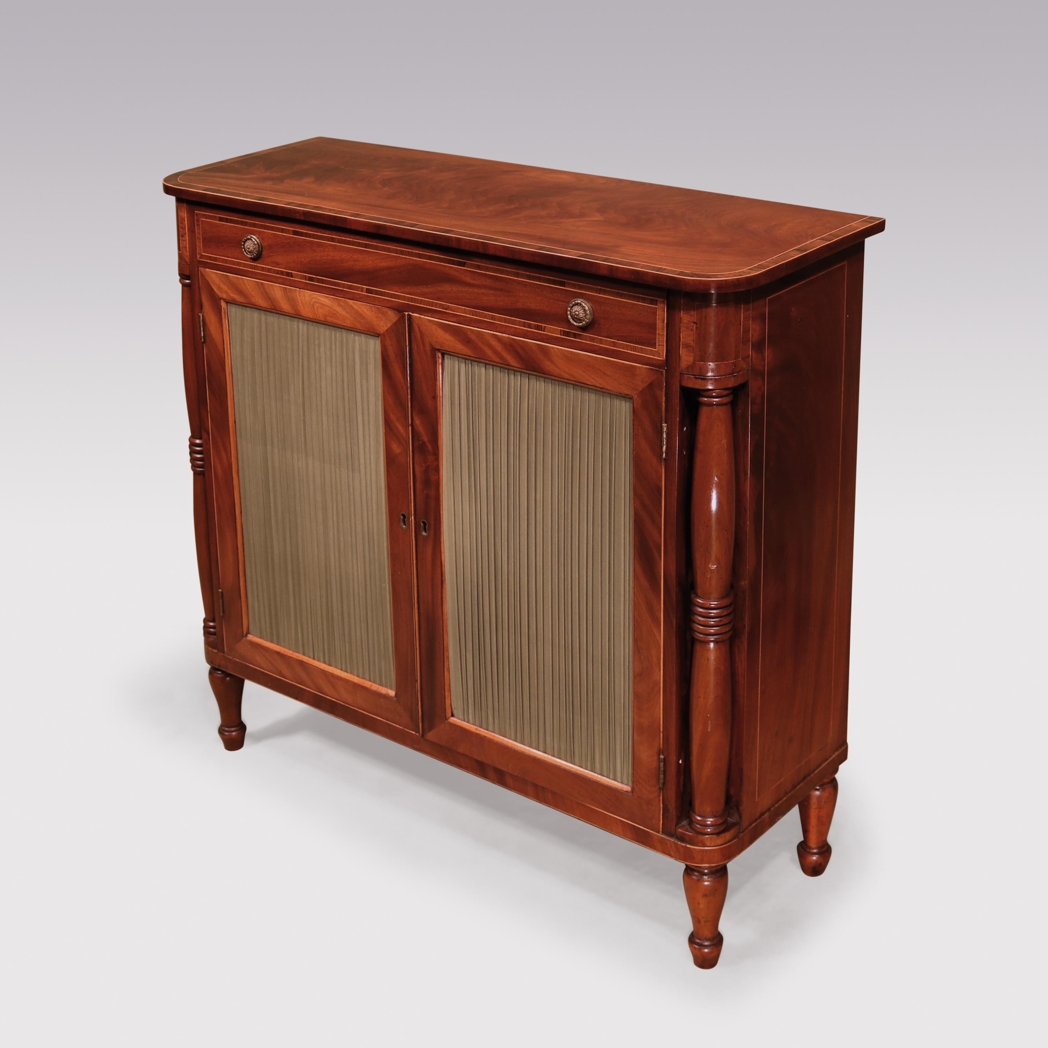 An early 19th Century Regency period figured Mahogany two door Cabinet, boxwood strung throughout having crossbanded ‘D’ shaped top above frieze drawer and pleated doors flanked by ring turned double baluster columns, supported on short turned feet.