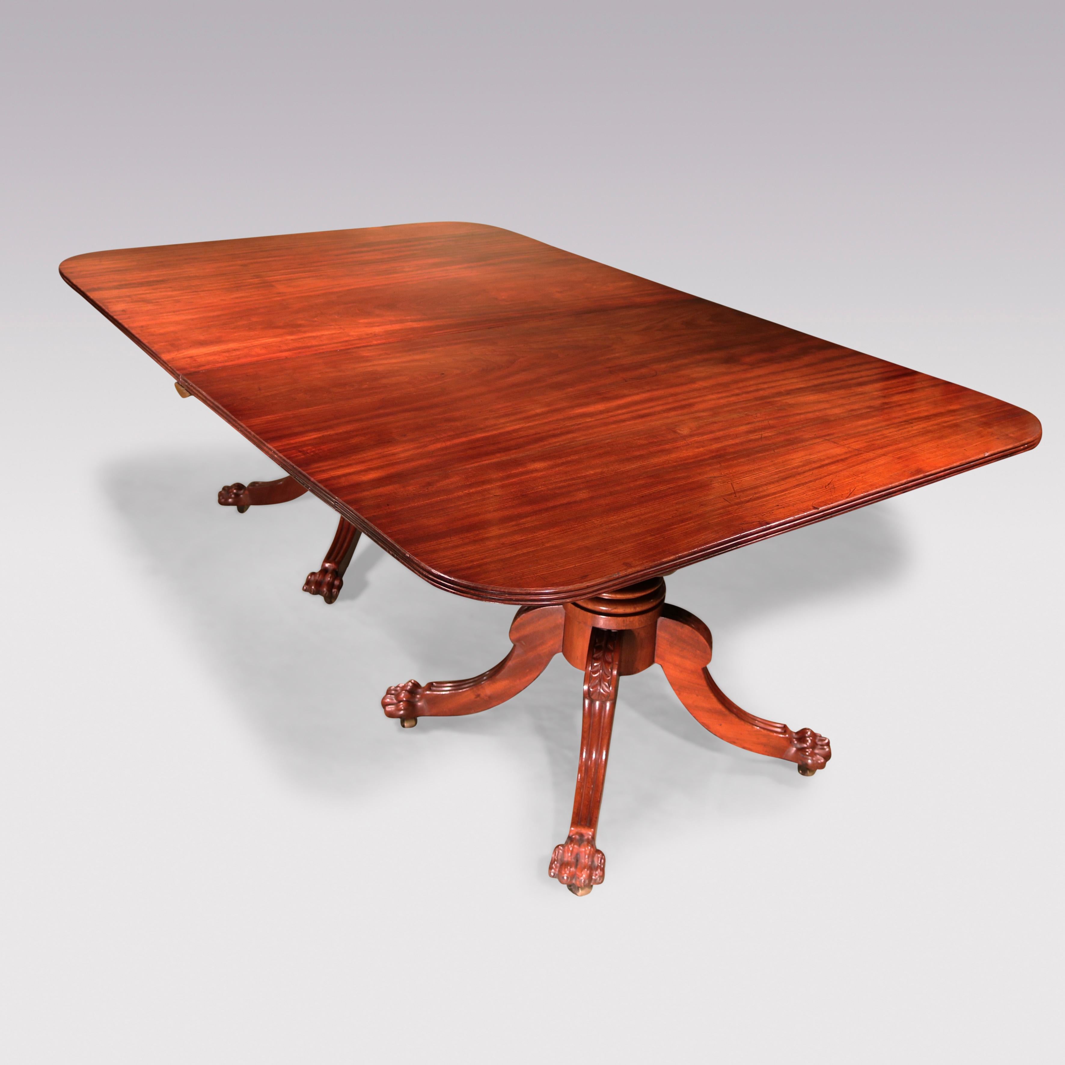 An early 19th century well-figured mahogany 2-pedestal Dining Table having reeded edged tops fitted with 2 contemporary leaves, supported on bold baluster turned stems ending on reeded acanthus carved 4-splay legs with carved paw feet ending on