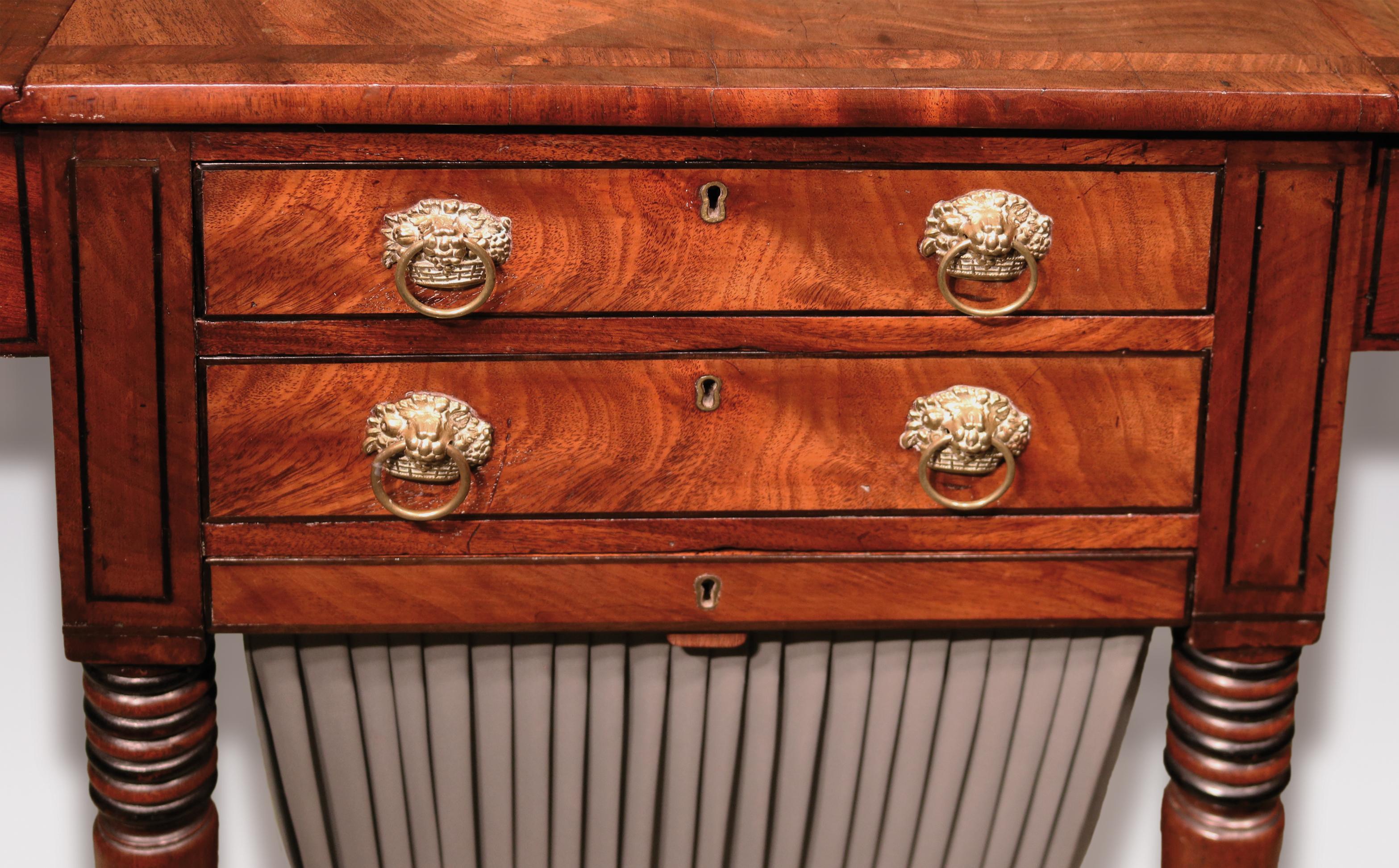 An attractive early 19th century Regency period flame figured mahogany work table, ebony strung throughout, having rectangular crossbanded top above frieze drawers retaining original “flower basket” handles, supported on ring-turned tapering legs