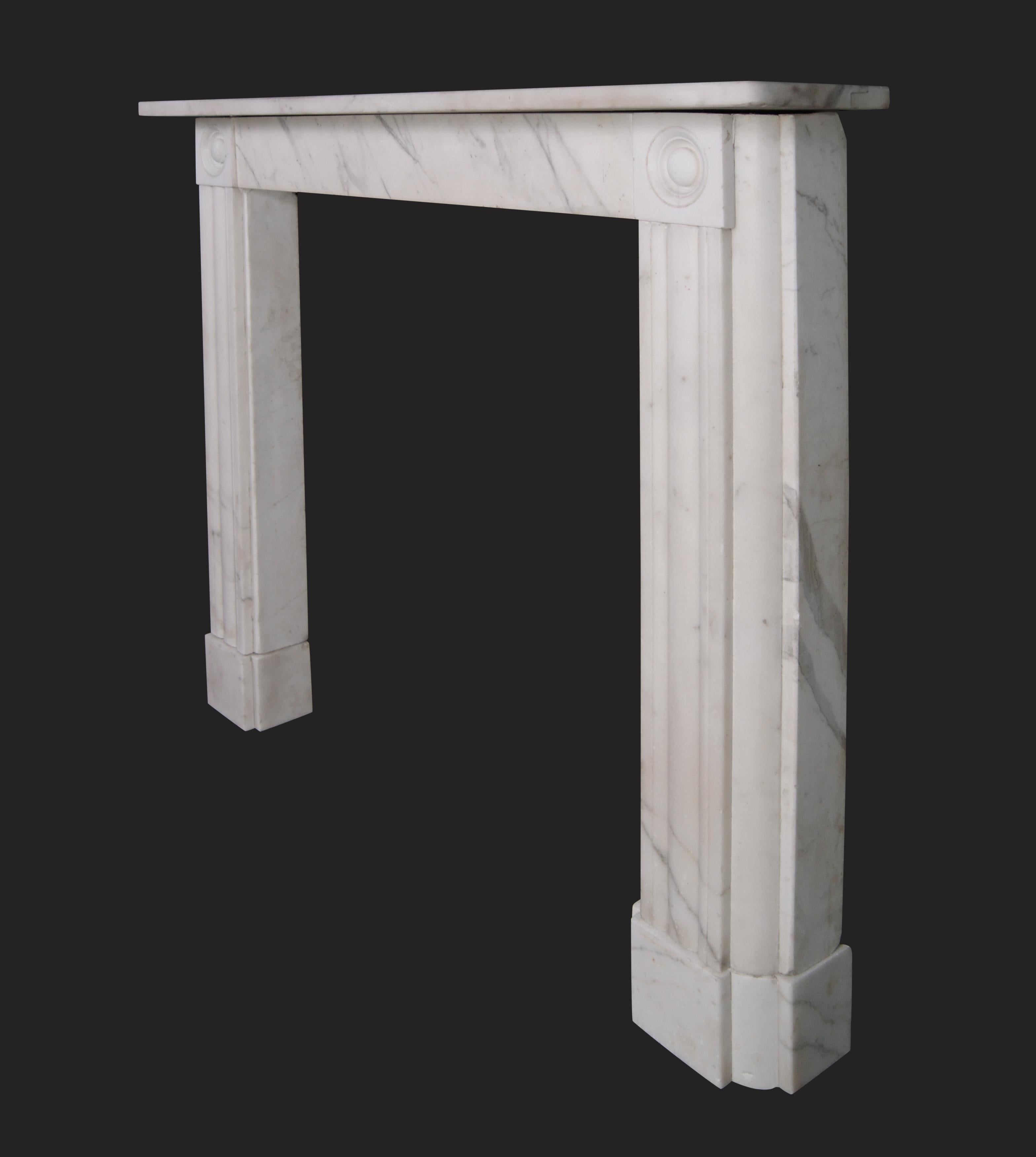 Cheminée en marbre d'époque Régence avec des jambages cannelés, une frise simple et des détails en ronde-bosse sur les blocs d'angle.  Plinthes en gradins pour rejoindre le foyer.
Largeur intérieure : 35.5