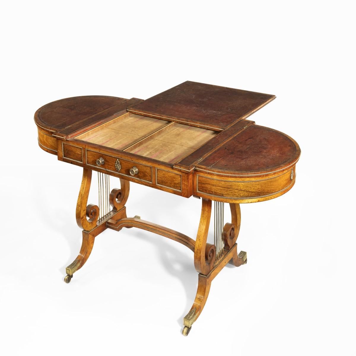A Regency period rosewood sofa games table attributed to Gillows of Lancaster; the top with rounded ends covered in the original distressed leather, with a central reversible chess board which can be removed to display a backgammon board beneath,