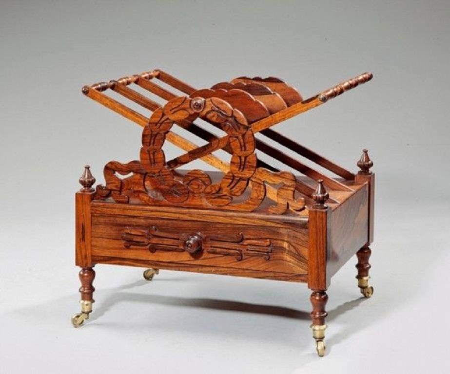 A Regency rosewood Canterbury in the manner of Loudon, with three divisions separated by pierced laurel wreaths and ribbons supported by crosses with turned stretchers, one side with a frieze drawer with wooden handles, raised on turned knop legs