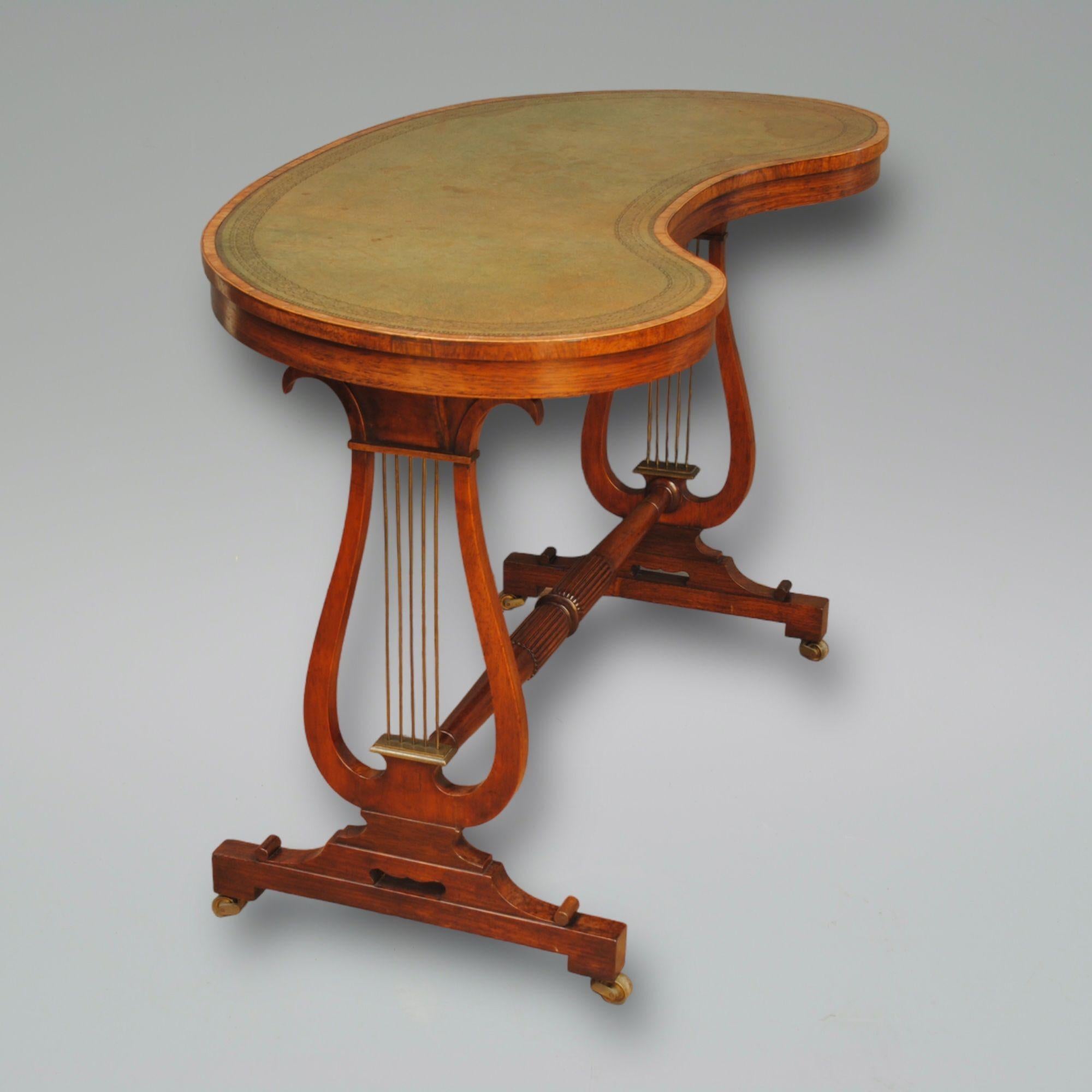 A regency period rosewood lyre eneded kidney shaped writing table, with brass lyres and leathered top.