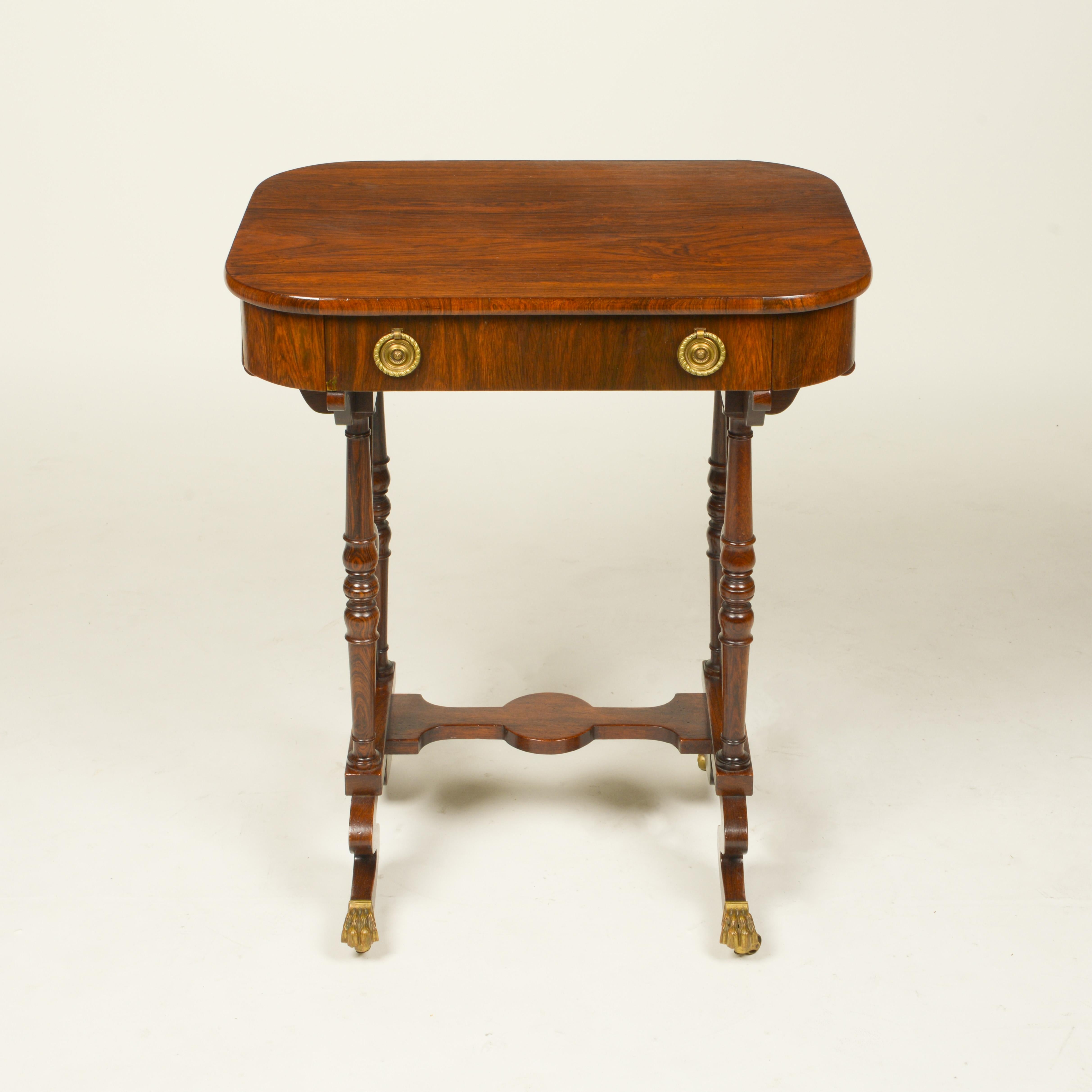 The rectangular top with rounded edges, fitted with a drawer with two brass pulls; the turned legs terminating in brass claw feet are joined by a small stretcher.