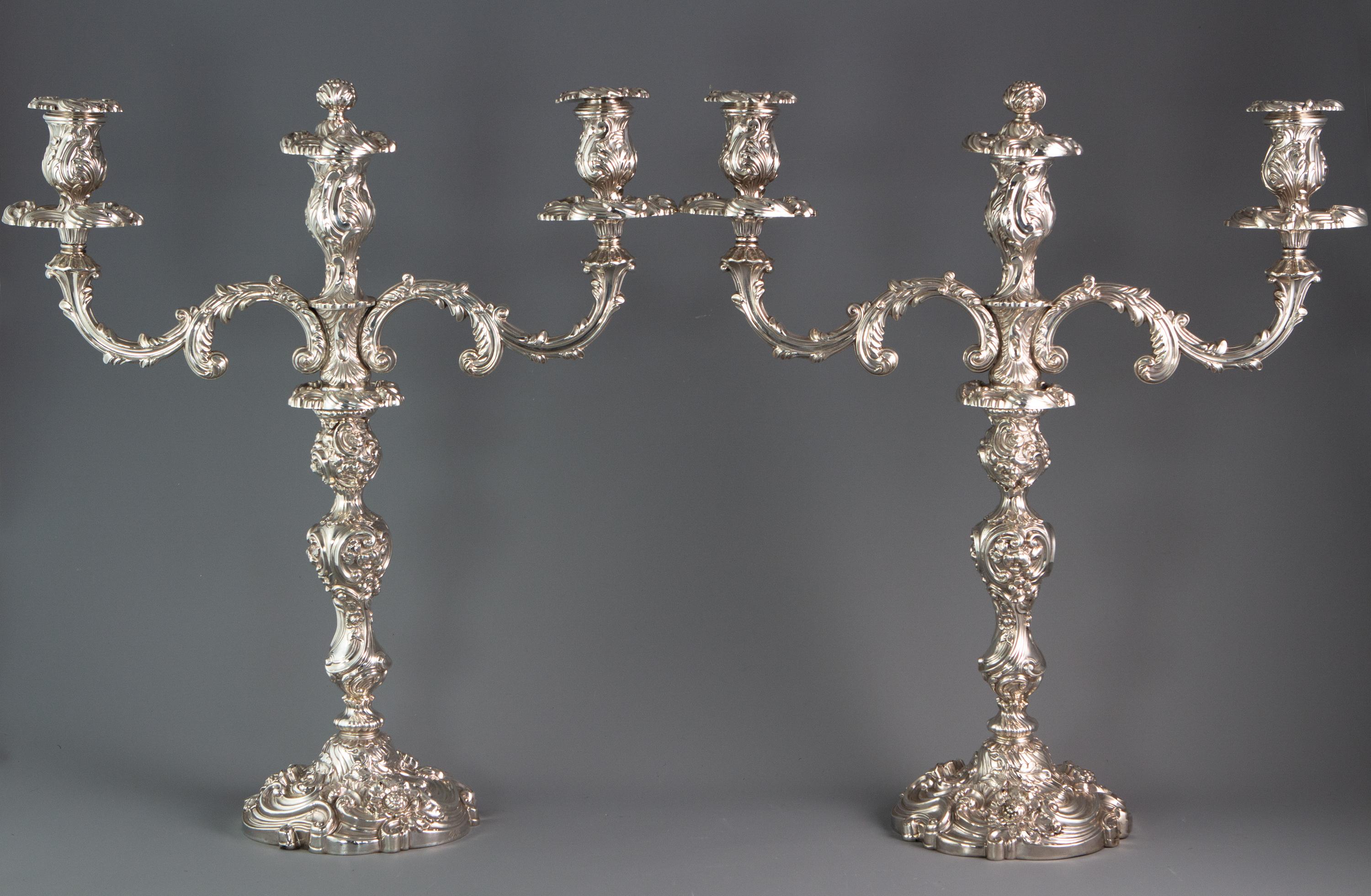 A superb table suite featuring a pair of 3-light candelabra with an accompanying pair of smaller candlesticks. All decorated in the Rococo manner with scrolling foliage, shells and roses, surmounted with a thistle decorated central snuffer. The