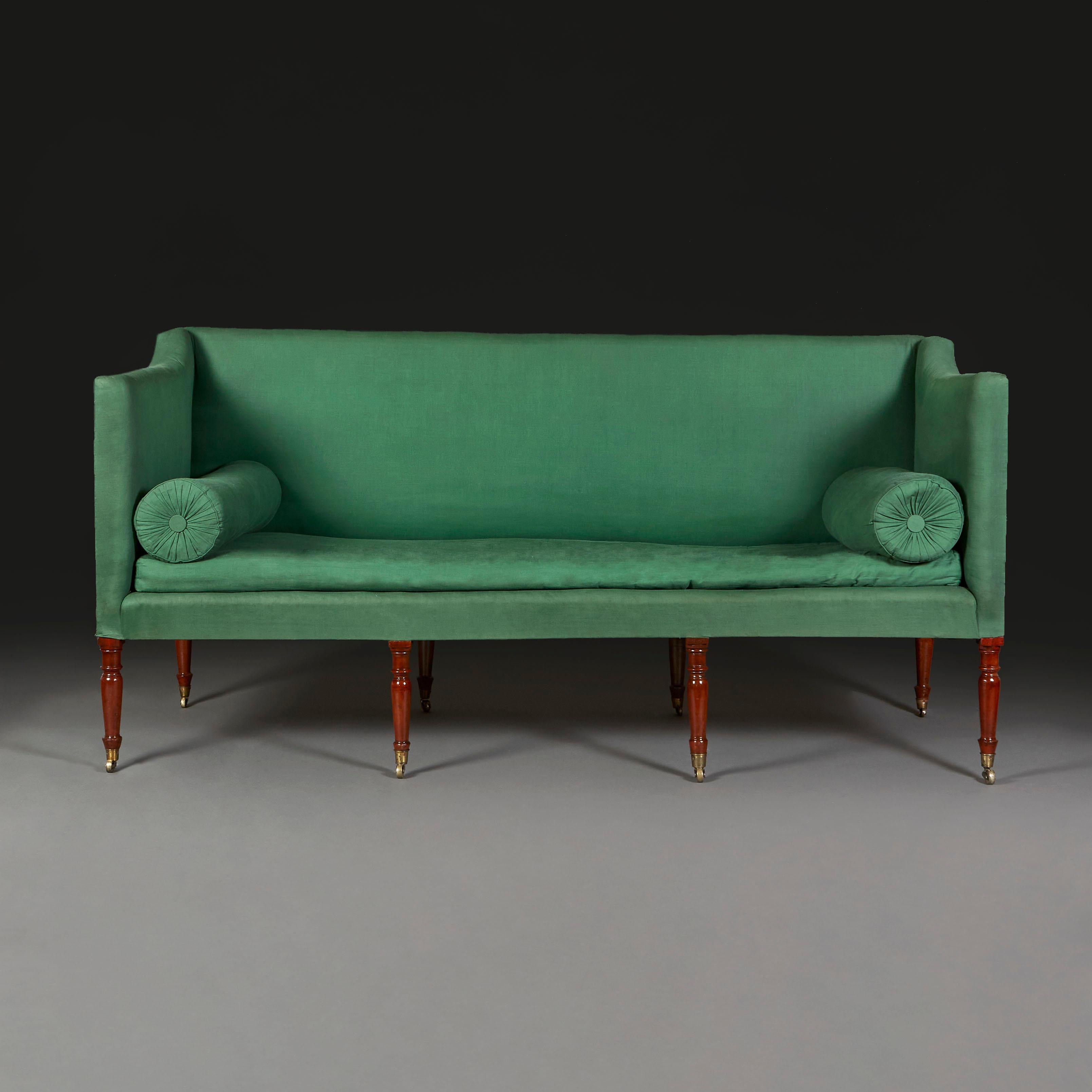 An early 19th century sofa of large proportions with 8 turned legs, terminating in brass castors, gently sweeping back and arms, with two boulster cushions and a squab cushion. Now requiring reuphostery.