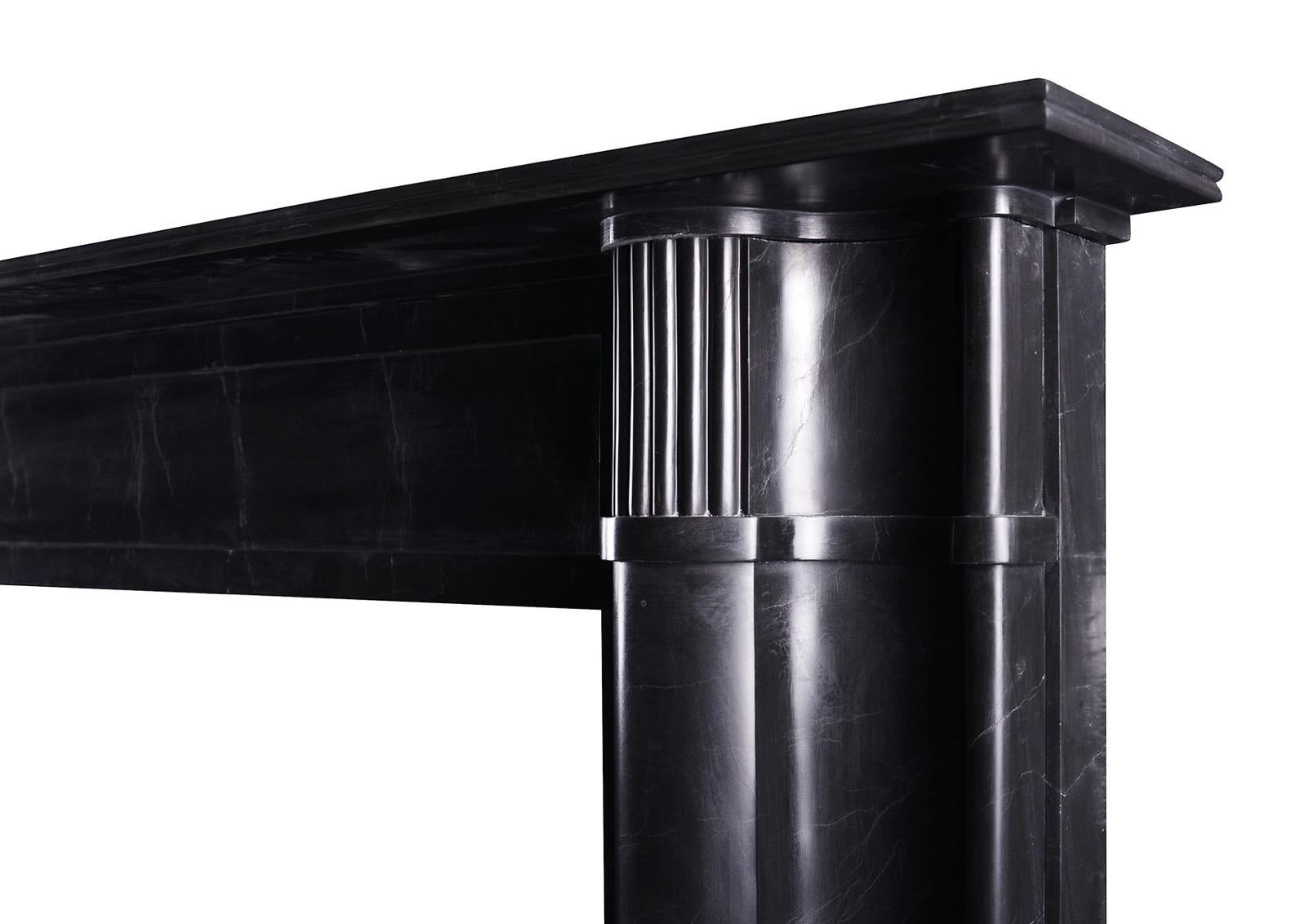 A Regency style black marble fireplace. The reeded jambs of bolection moulding, the frieze with centre panel surmounted by reeded shelf. A copy of a period piece, which could be equally at home in a classical or contemporary setting. English,