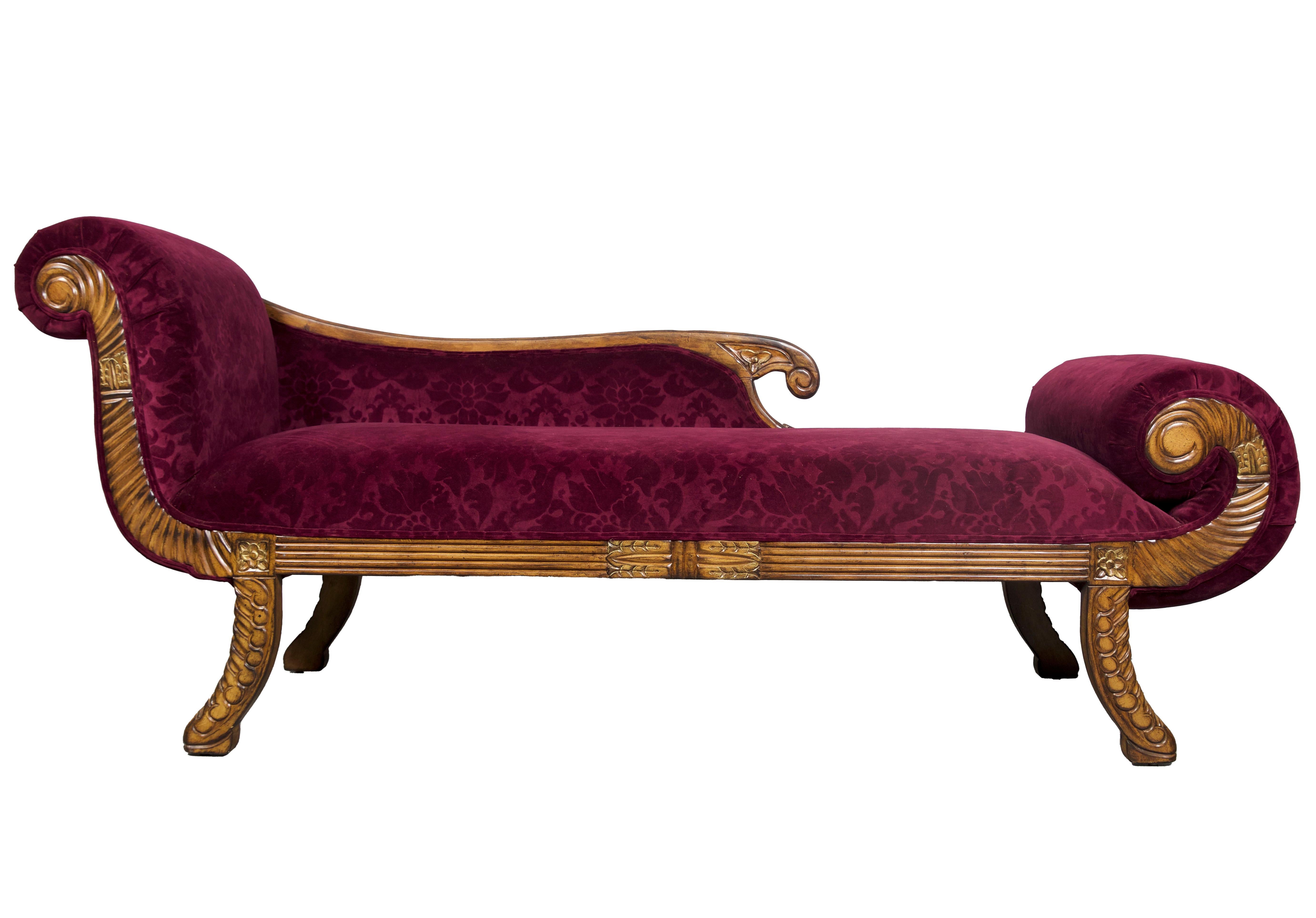A Regency style upholstered carved day bed. The characteristic include a sleigh-style or scrolled back, scrolled arms, and intricately carved details on the legs and frame, echoing the neoclassical influences of the Regency period. The upholstery is