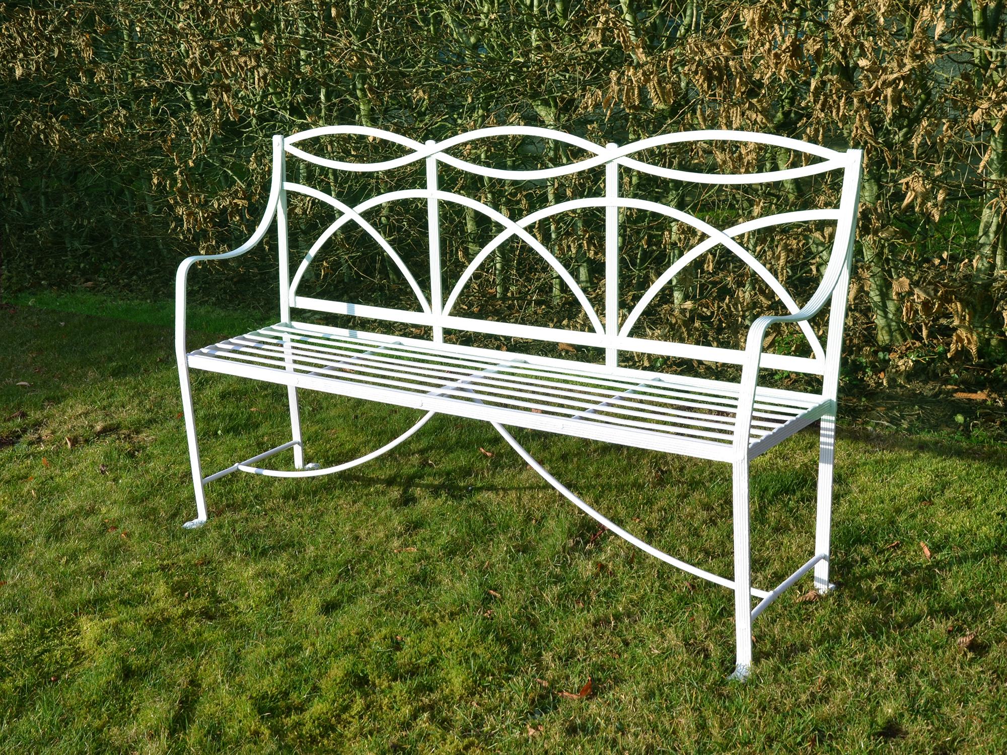 A Regency wrought iron garden seat constructed of reeded strips of iron brazed and pinned to form the classic arch back, straight slat seat with curved arm rests.